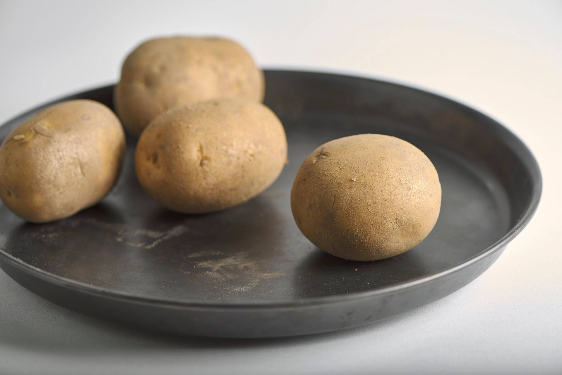 three potatoes on a baking pan with white background