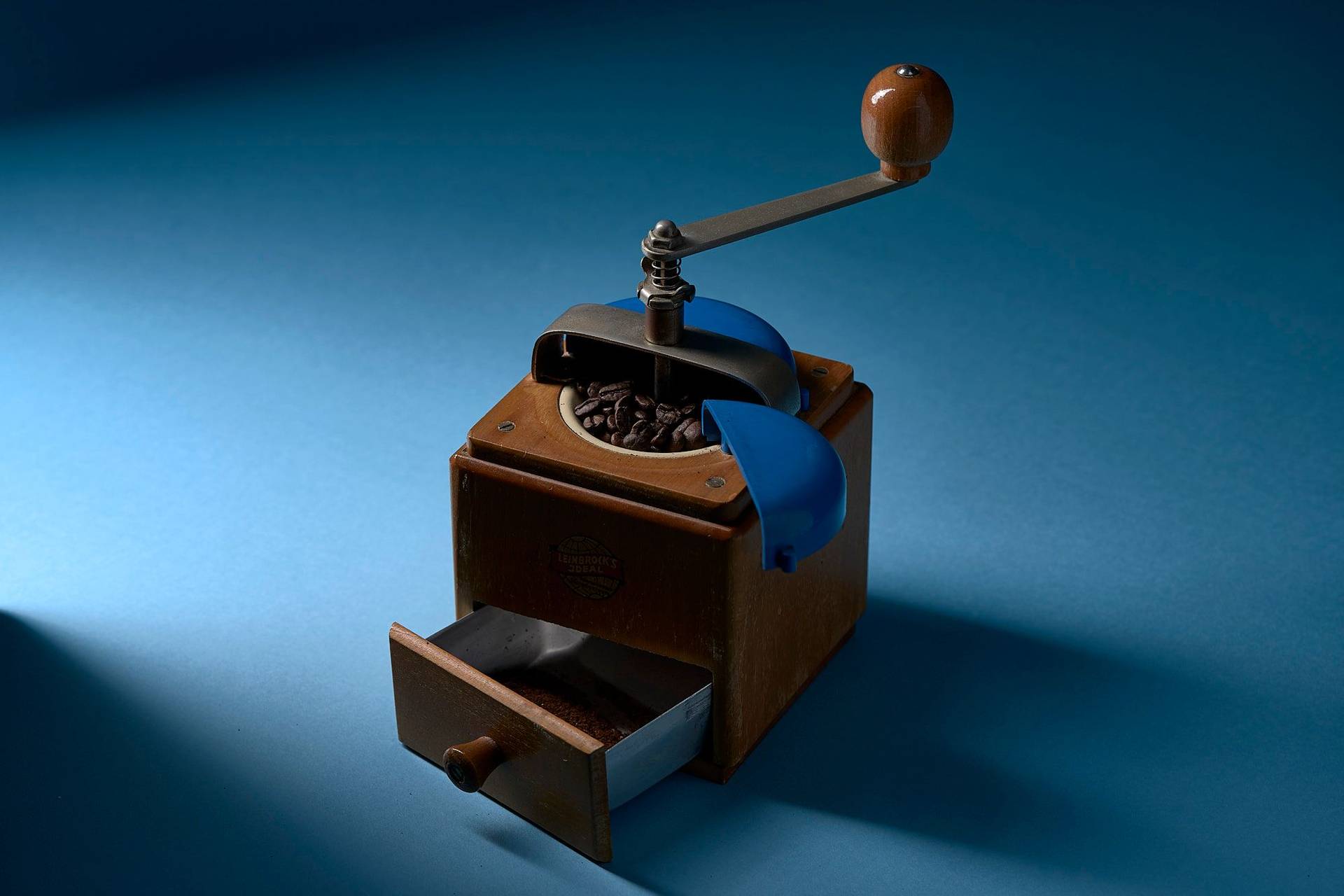 frisch gemahlener kaffee in einer vintage kaffeemühle mit blauem hintergrund