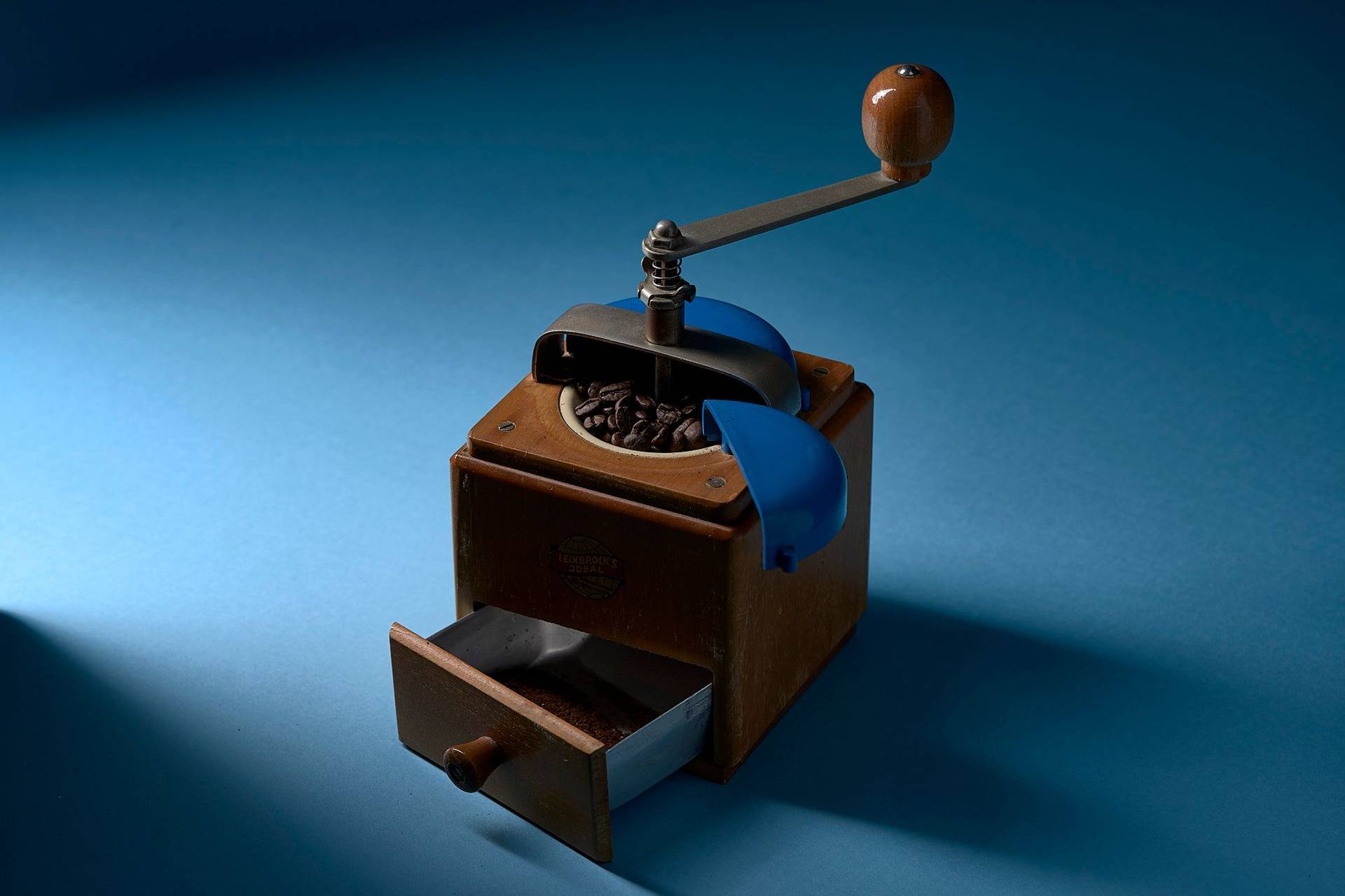 coffee ground coffee in a vintage hand mill with blue background