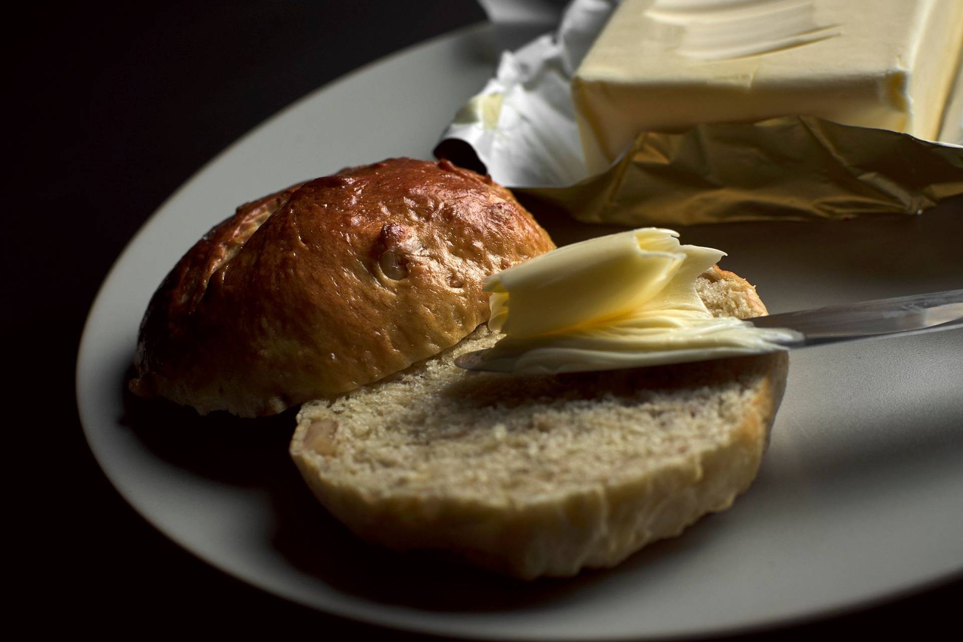 brioche bun with walnuts on a plate with butter and black backgound