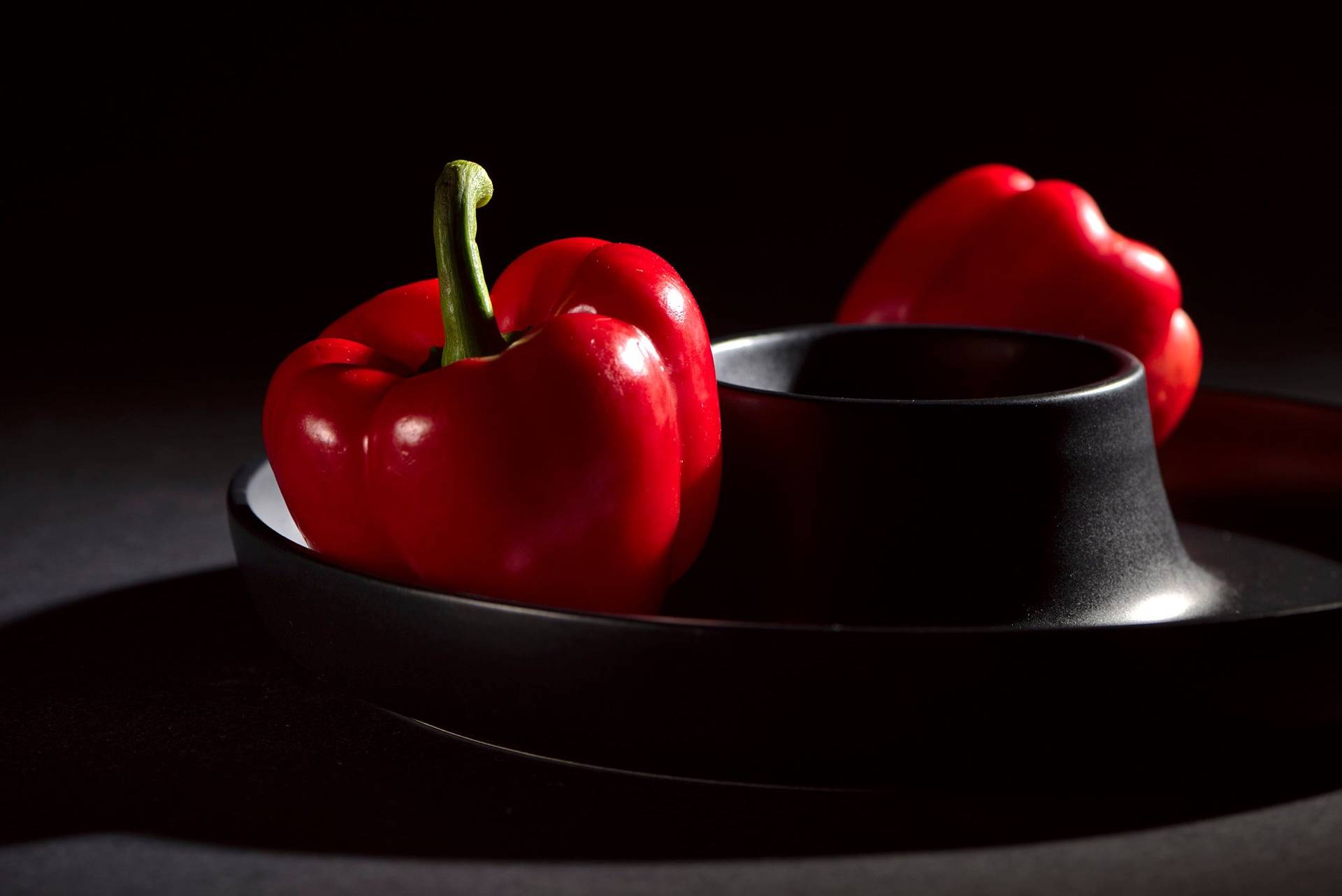 two bell peppers on black background