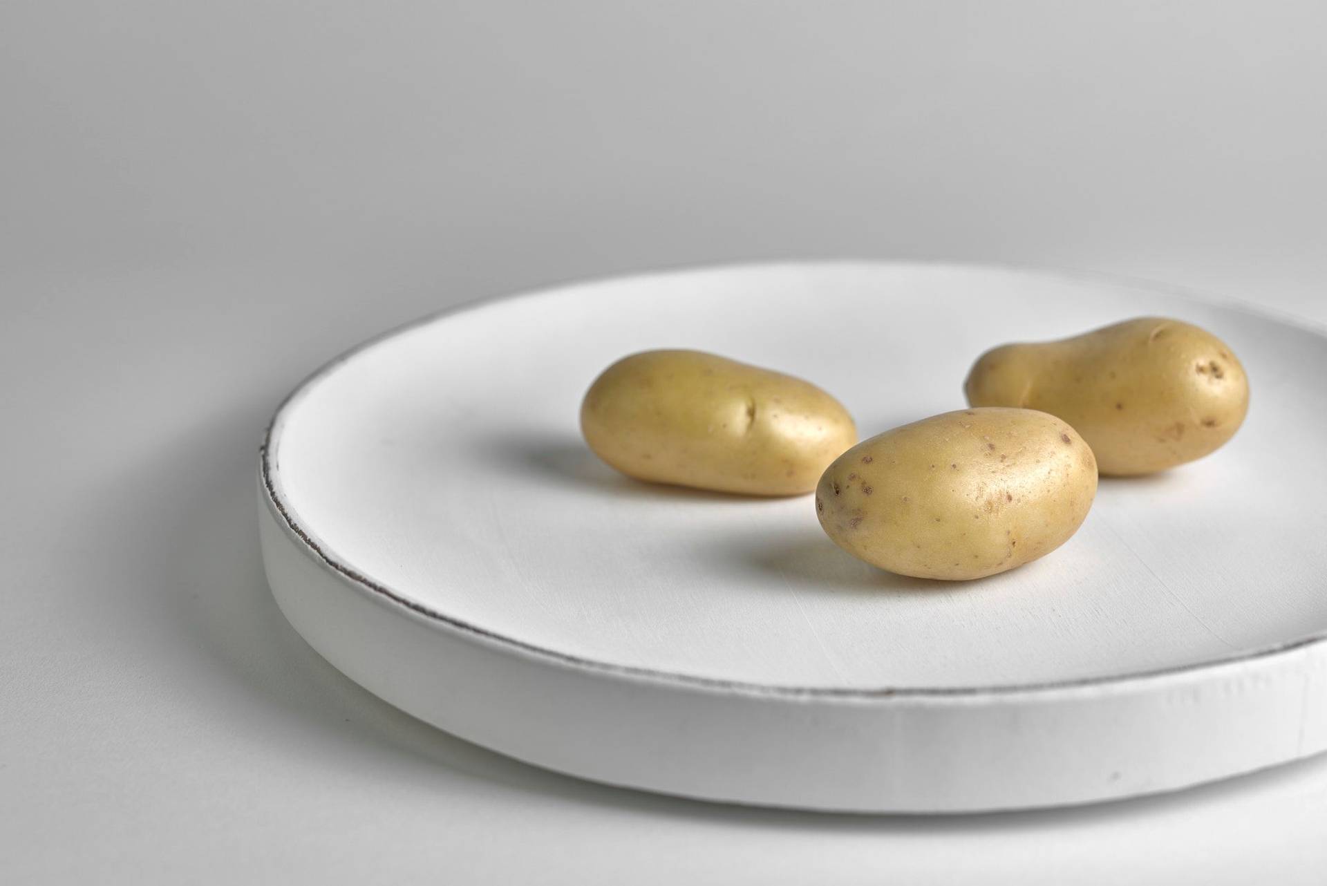 three potatoes on a white plate with white background