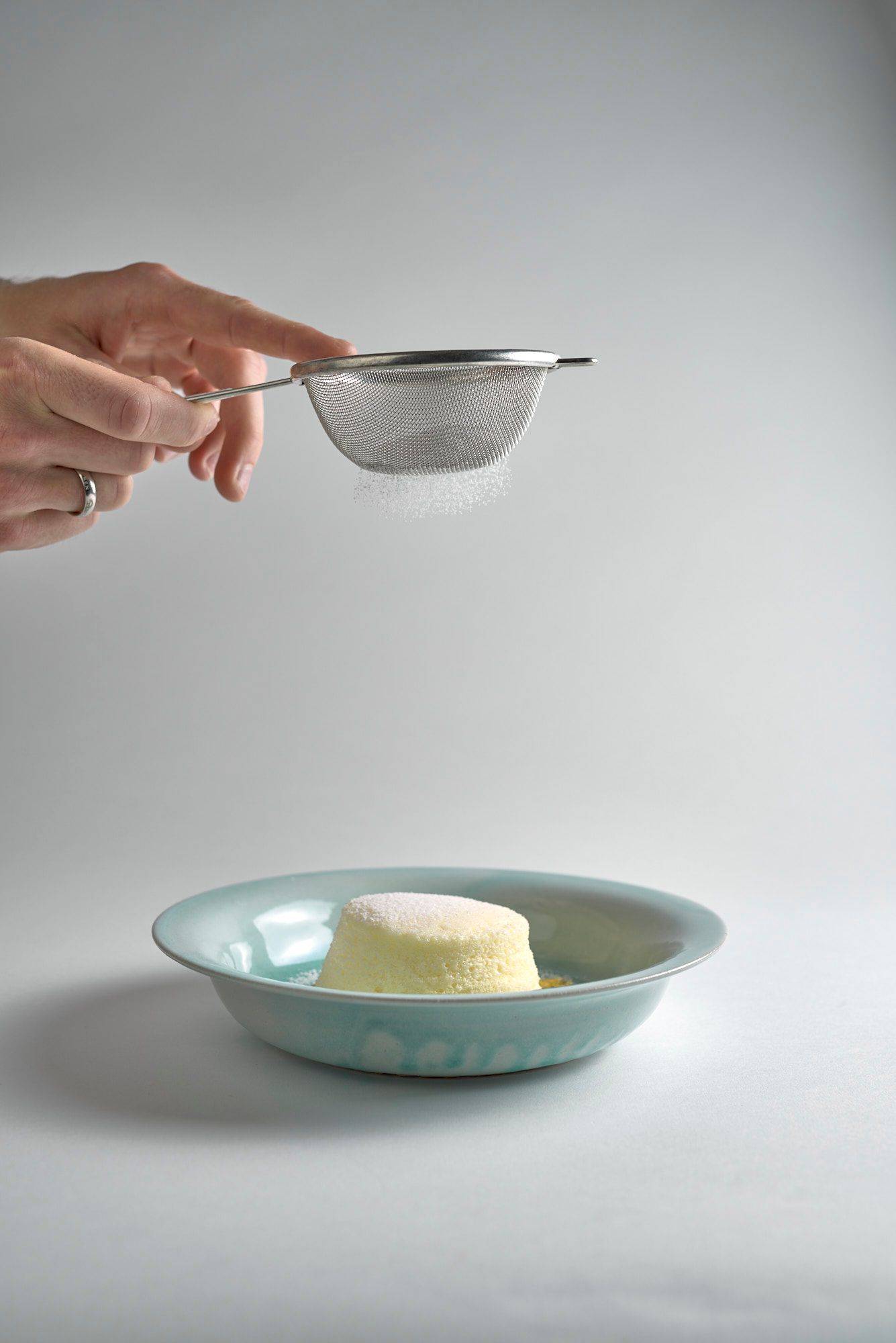 cheesecake souffle with passion fruit and linseed oil in a turquoise plate with white background