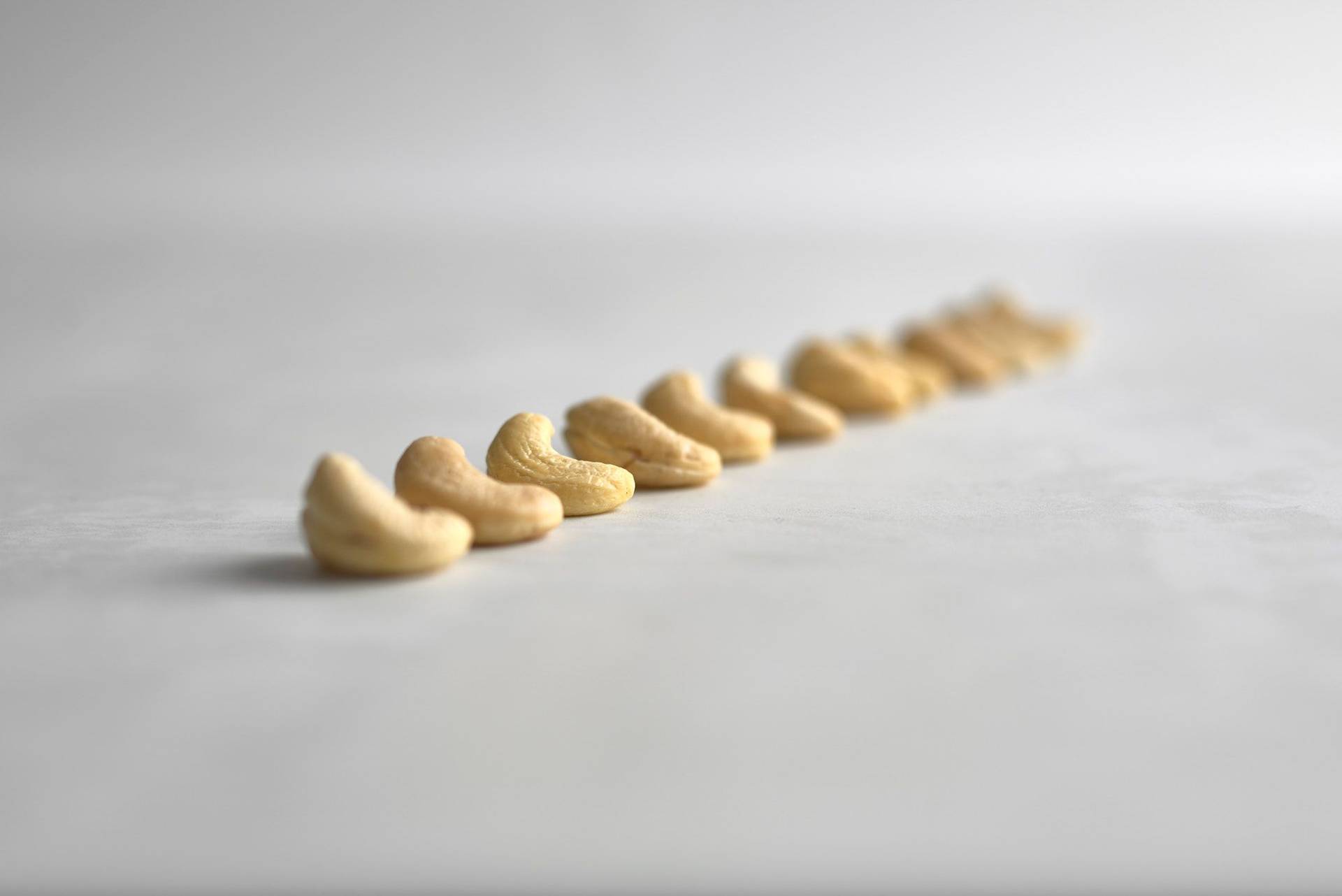 cashew nuts in a row on a white sapienstone top