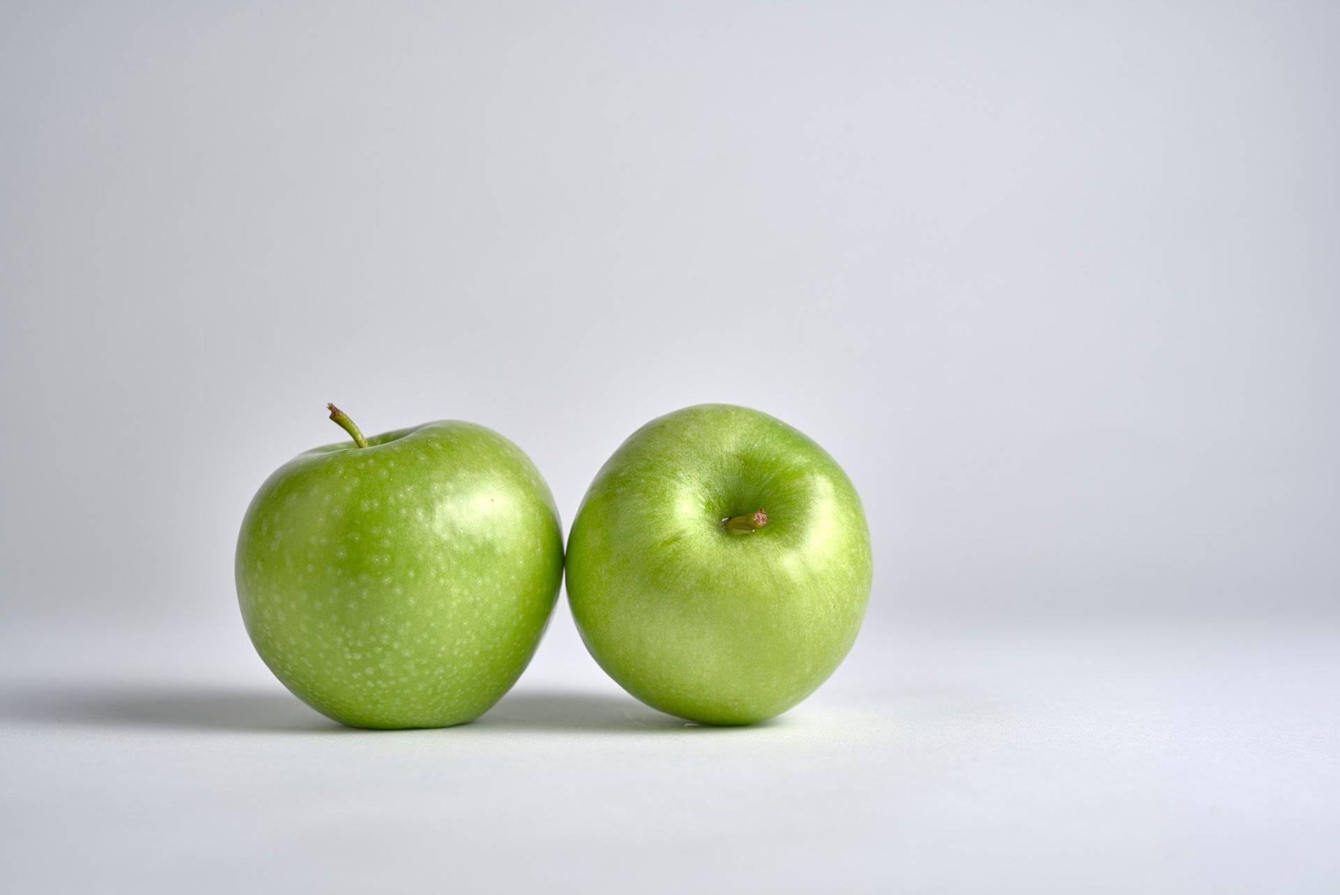 zwei grüne äpfel mit weißem hintergrund