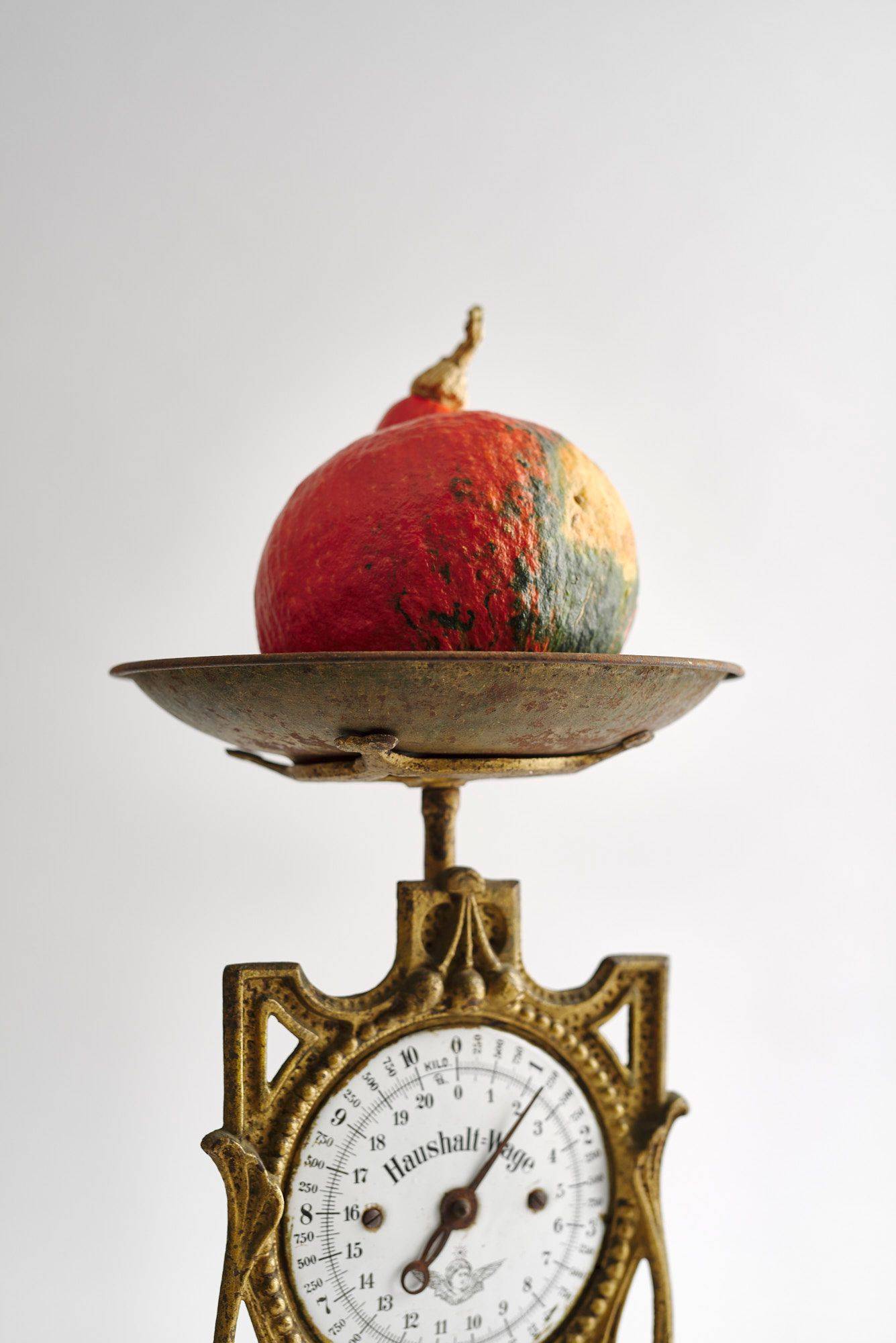 a hokkaido pumpkin on a vintage scale with white background