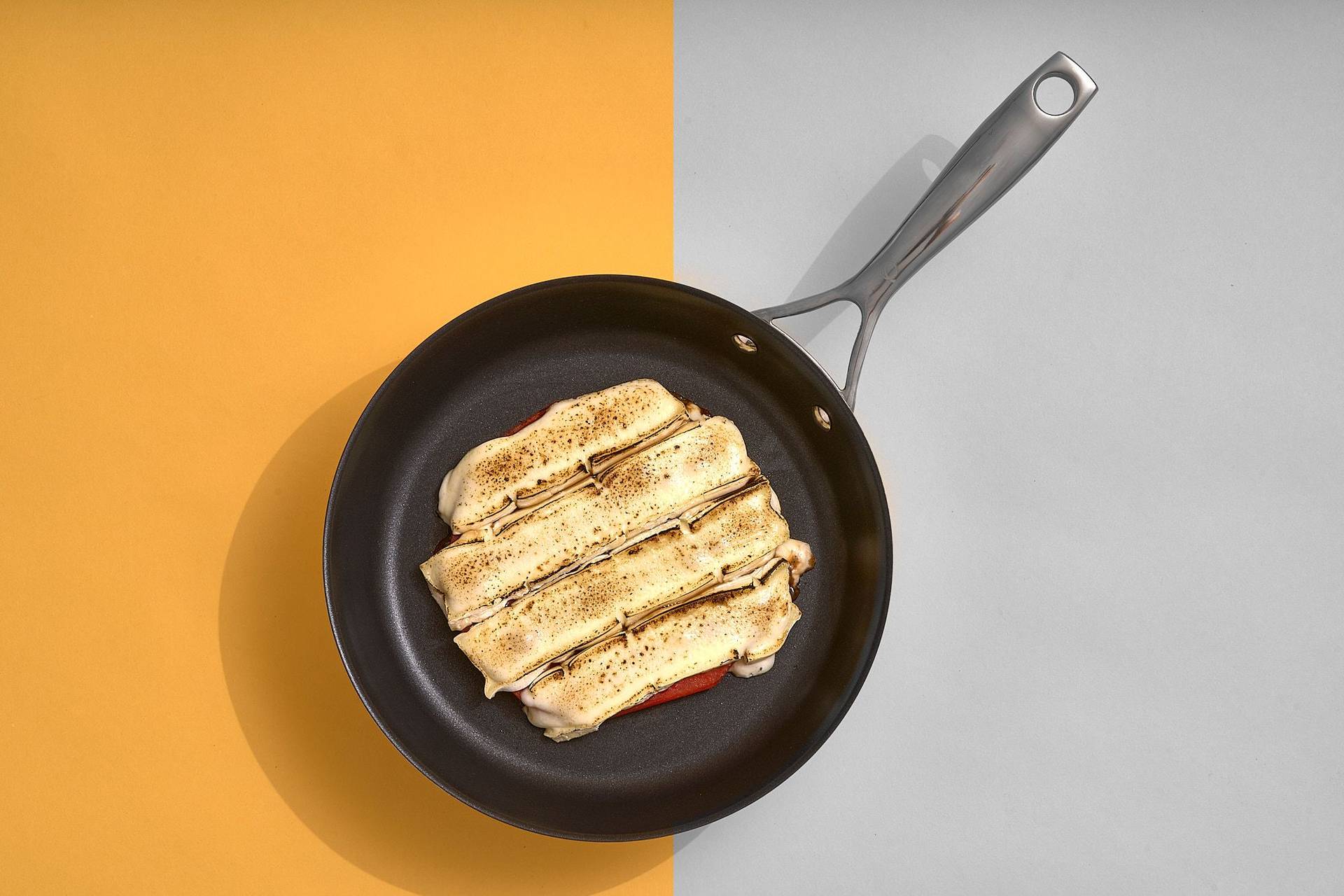 gegrillte wassermelone mit käse gratiniert in einer pfanne auf gelbem untergrund