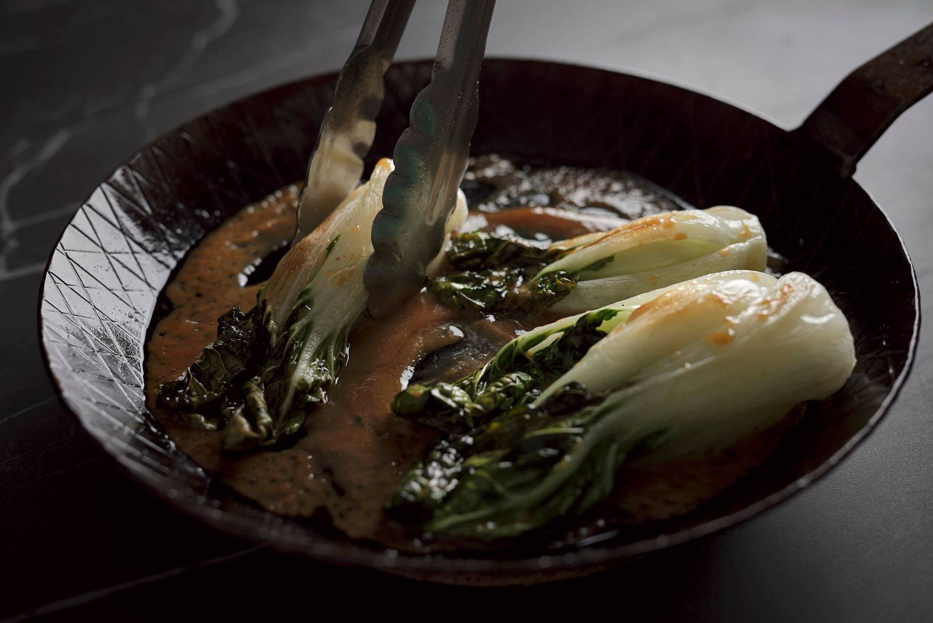 miso roasted pak choi in a cast iron pan on a gray sapienstone top