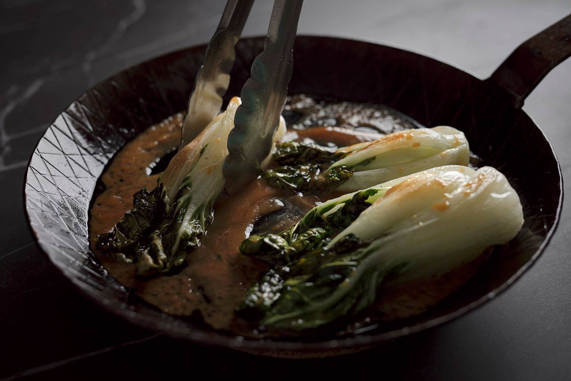 miso geschmorter pak choi in einer gusseisen pfanne auf einem sapienstone top