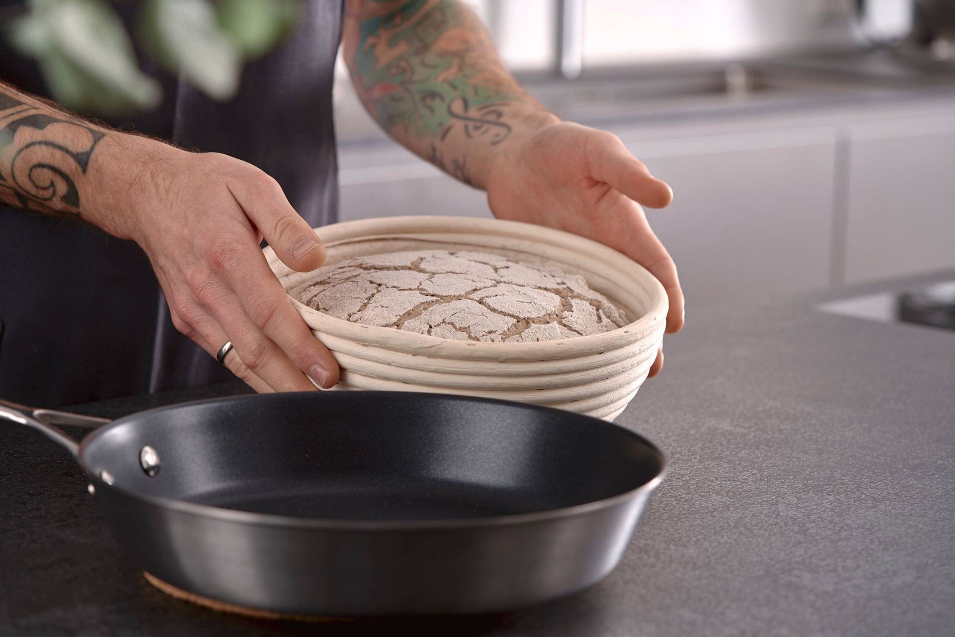 man holds proofed rye sourdough bread in home kitchen