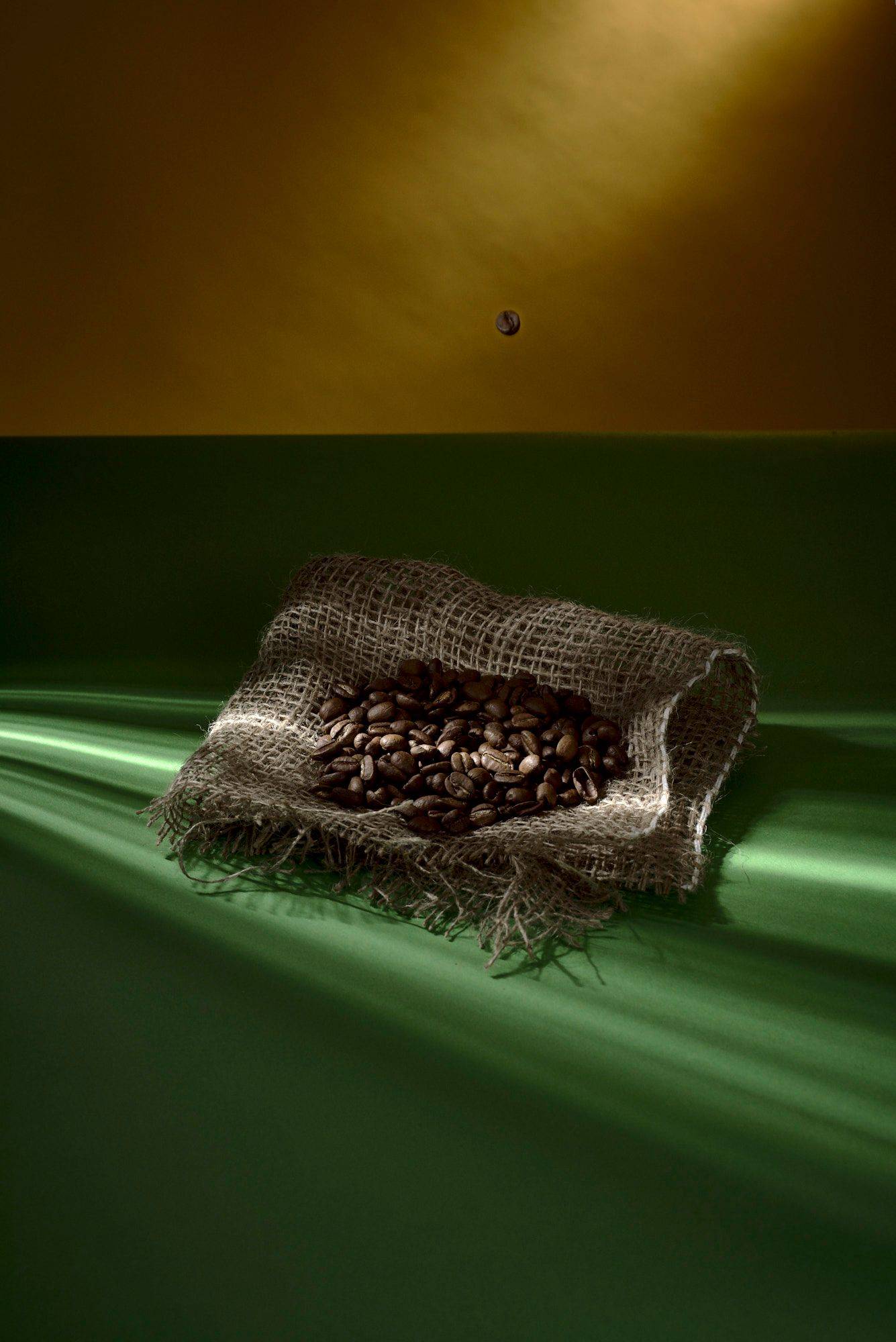kaffeebohnen auf einem jutesack mit grün gelbem hintergrund