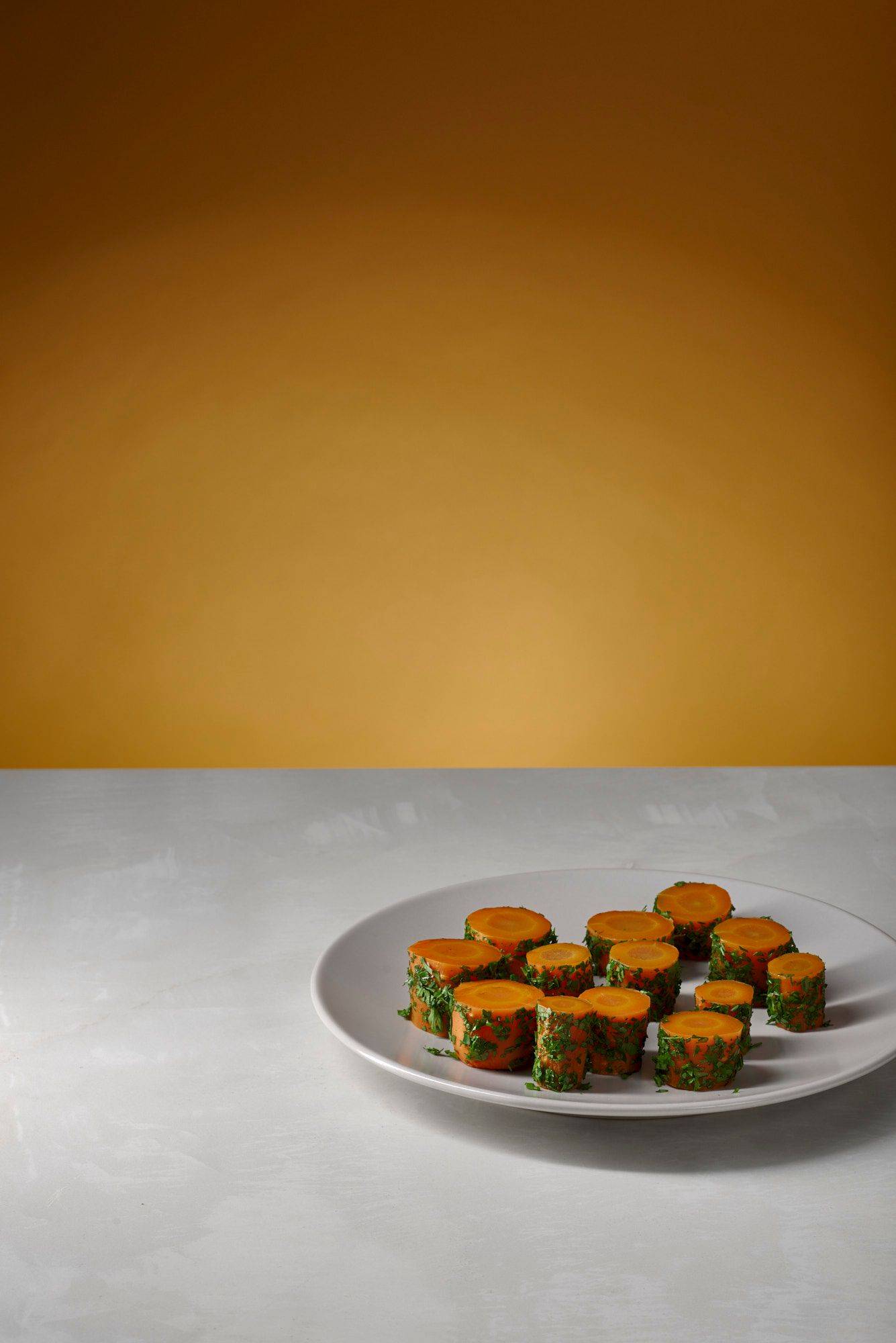 hay carrots on a white plate with white sapienstone top and yellow background