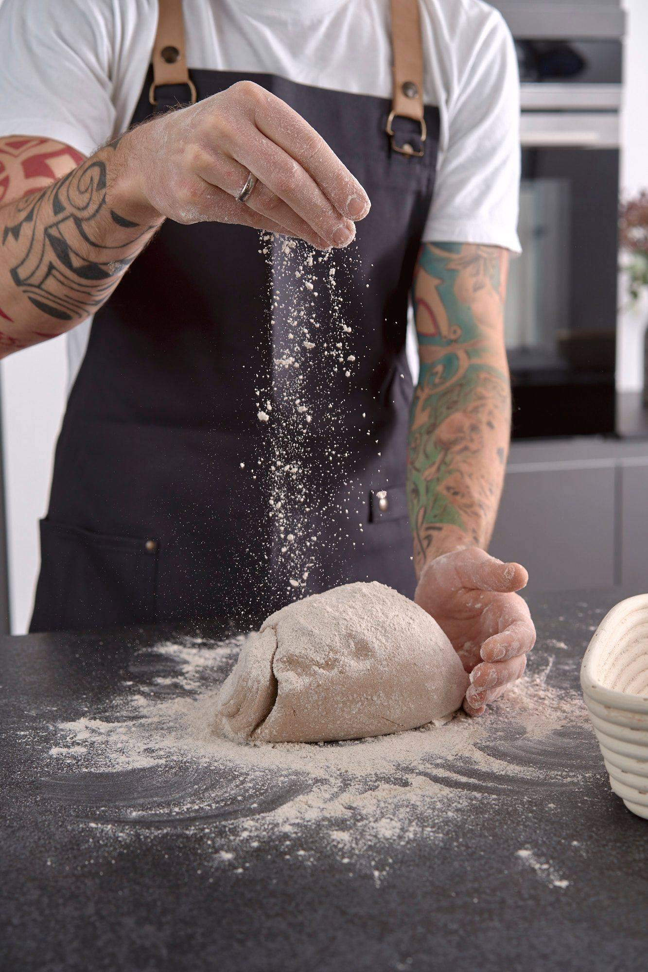 man is kneading rye sourdough in home kitchen