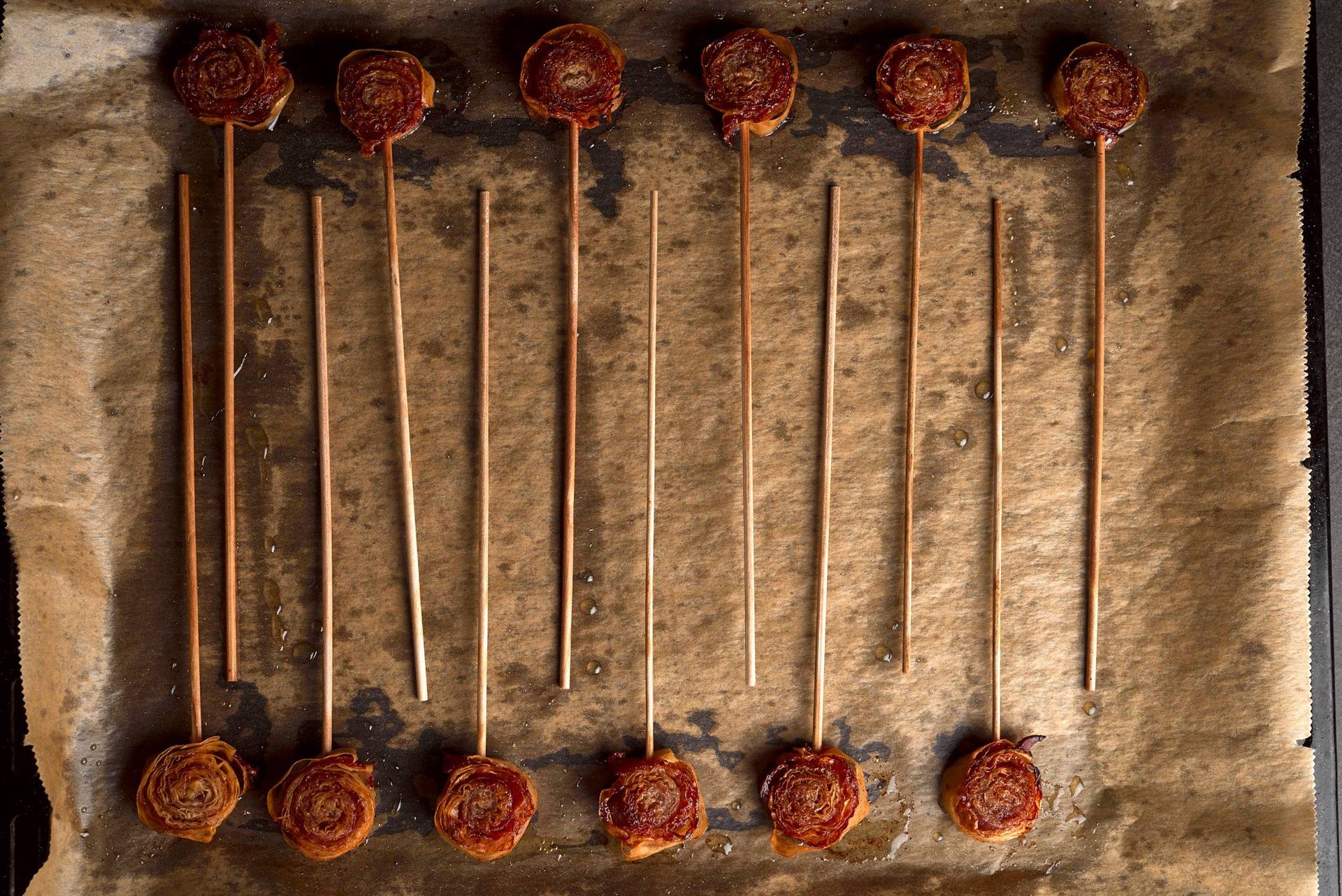 baked bacon and cinnamon lollipops on a baking sheet