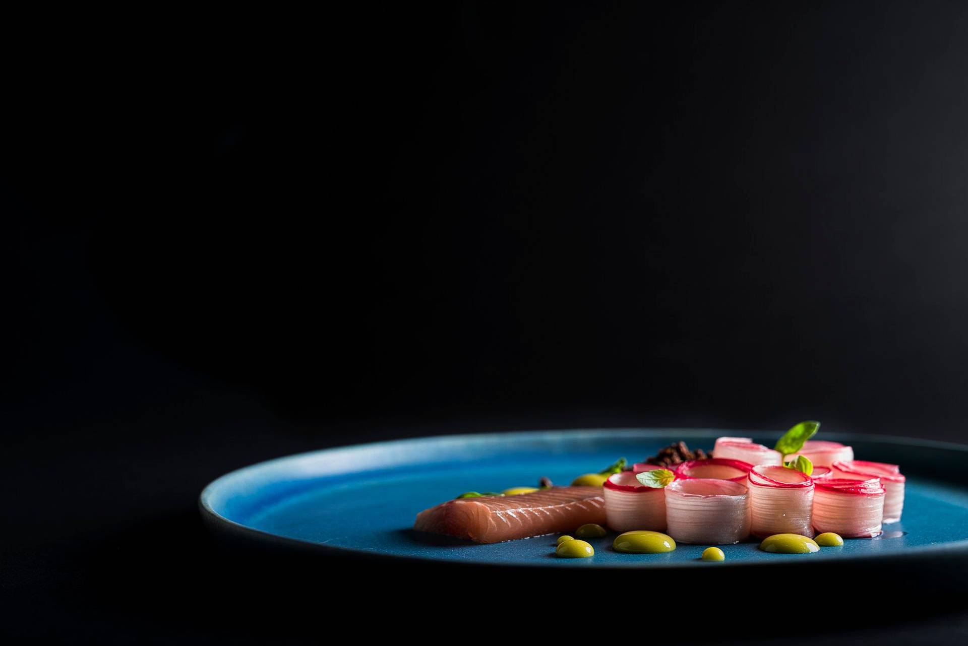 basil and orange cured char with rhubarb and tea mayonnaise on a blue plate with black background
