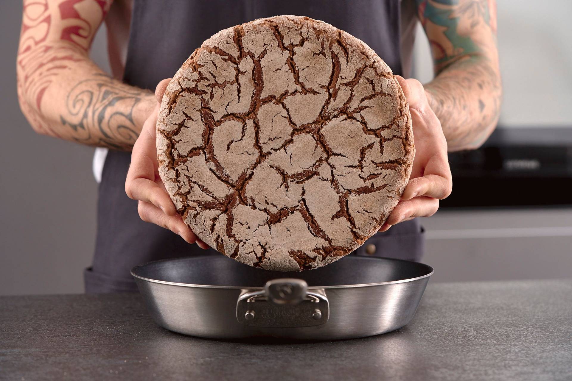 man holds a pan baked rye sourdough bread in home kitchen