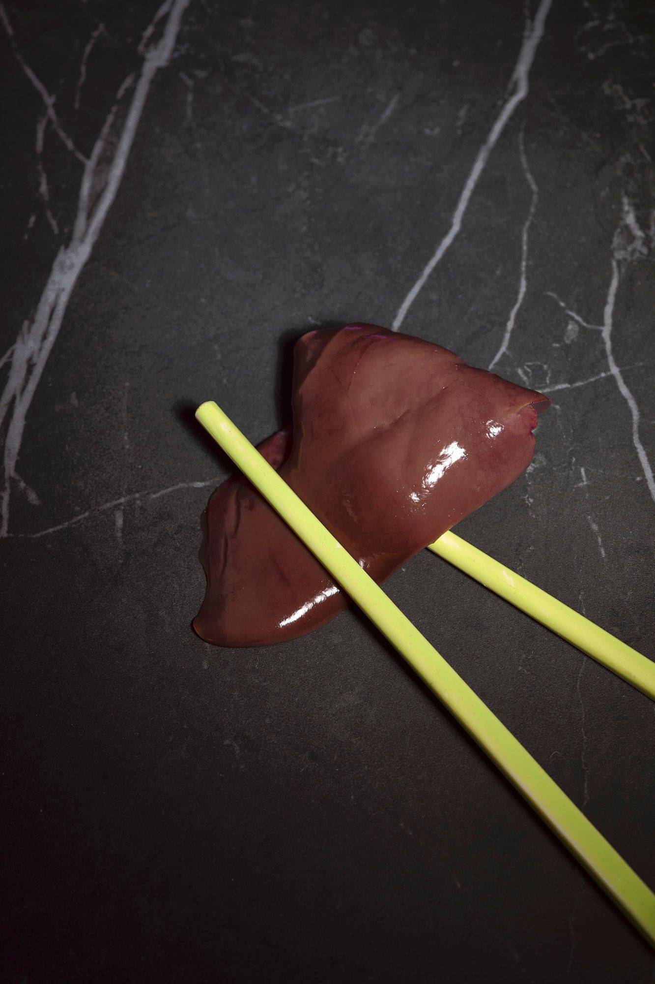 raw chicken liver with yellow chopsticks on a gray marbled sapienstone top 