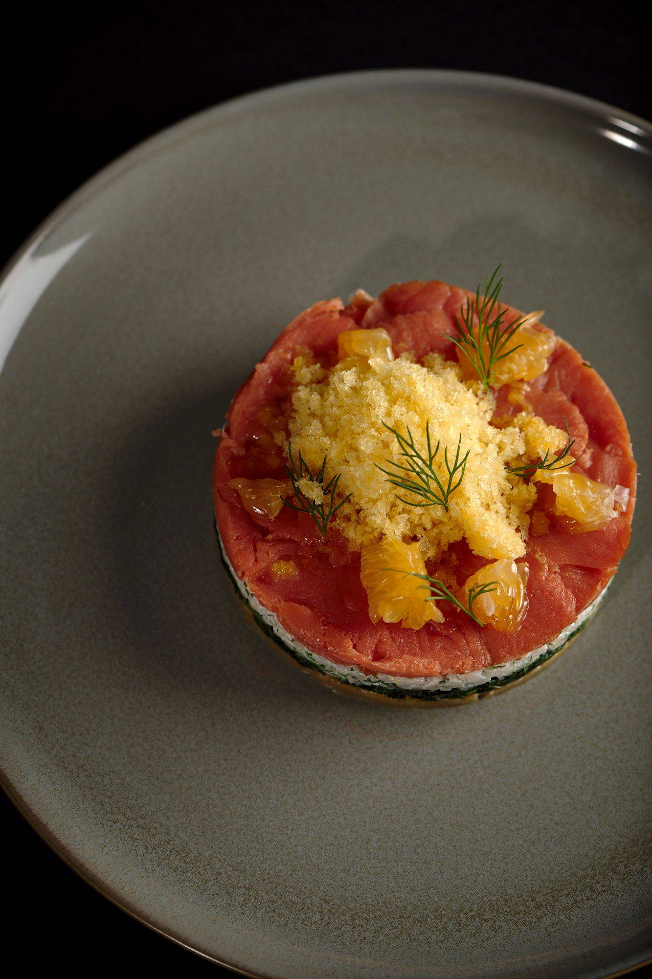 gebeizte lachs tarte mit mandarinen granita auf einem grauen teller mit schwarzem hintergrund