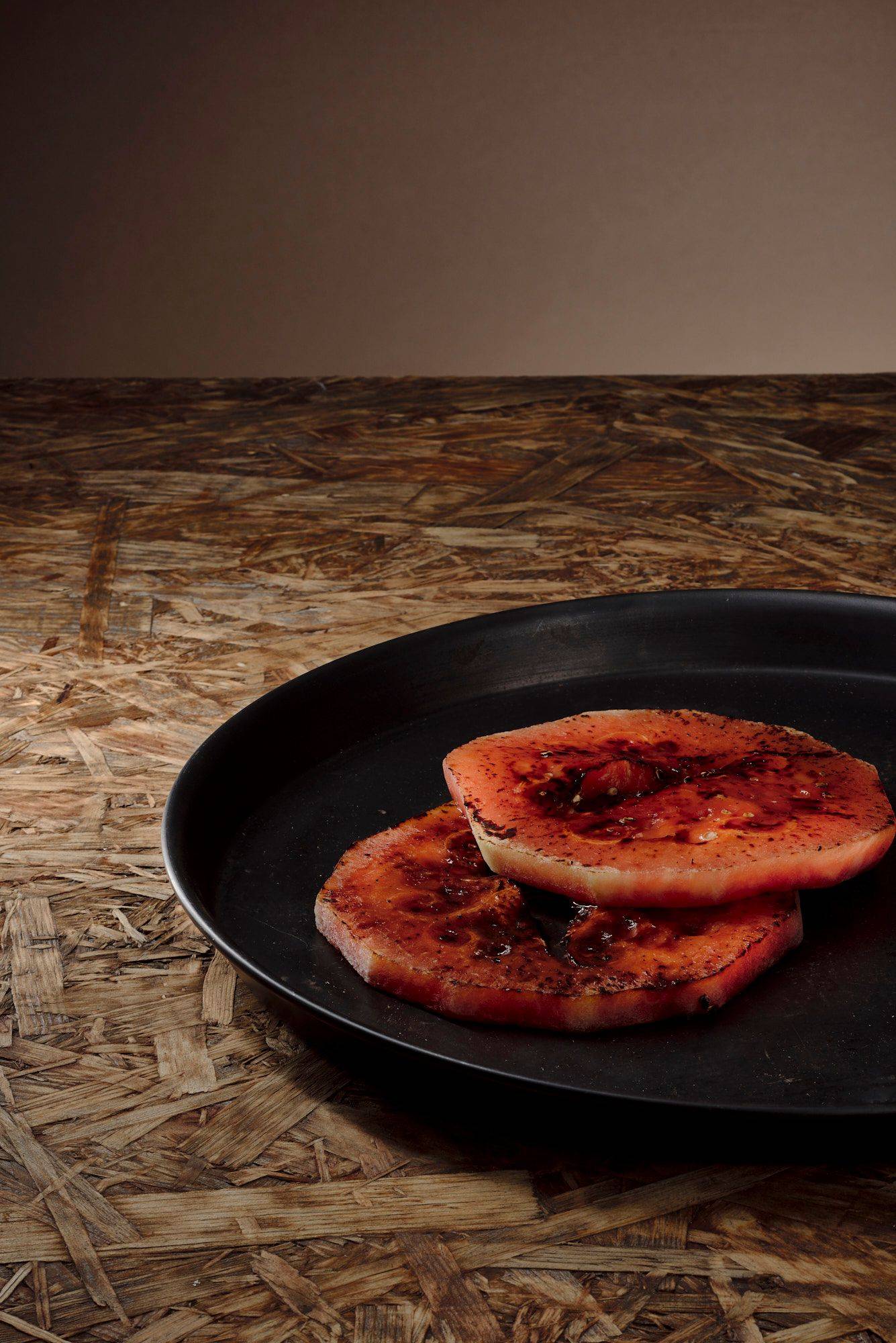 grilled watermelon on a baking pan with brown wooden background