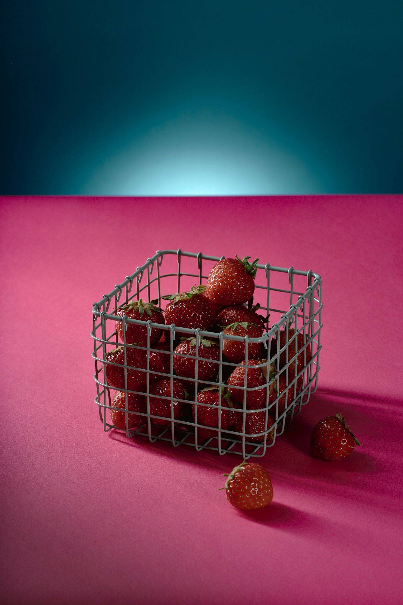 erdbeeren ein kleiner korb mit erdbeeren mit pinkem und blauem hintergrund