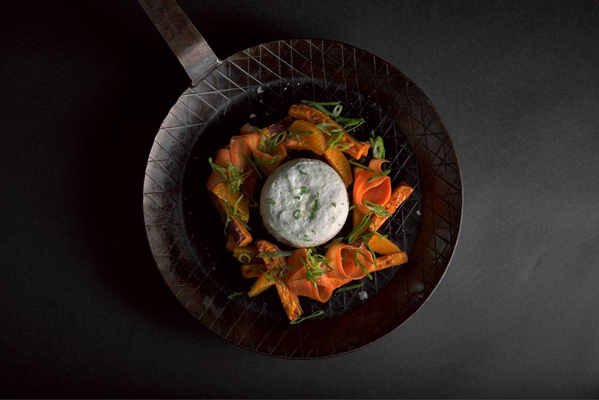 savory egg souffle with sweet potatoes and pickled carrots in a cast iron pan on black background