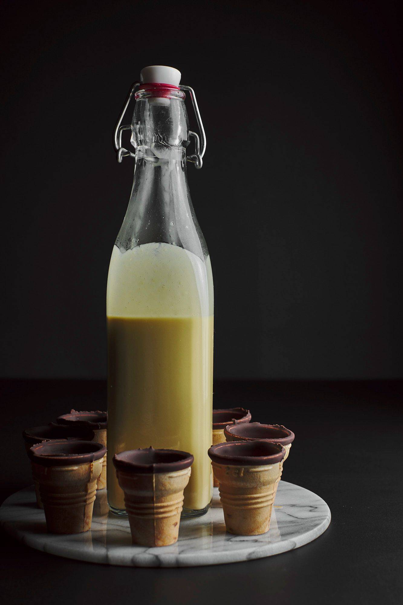 homemade eggnog with chocolate waffer cups on a marble plate with black background