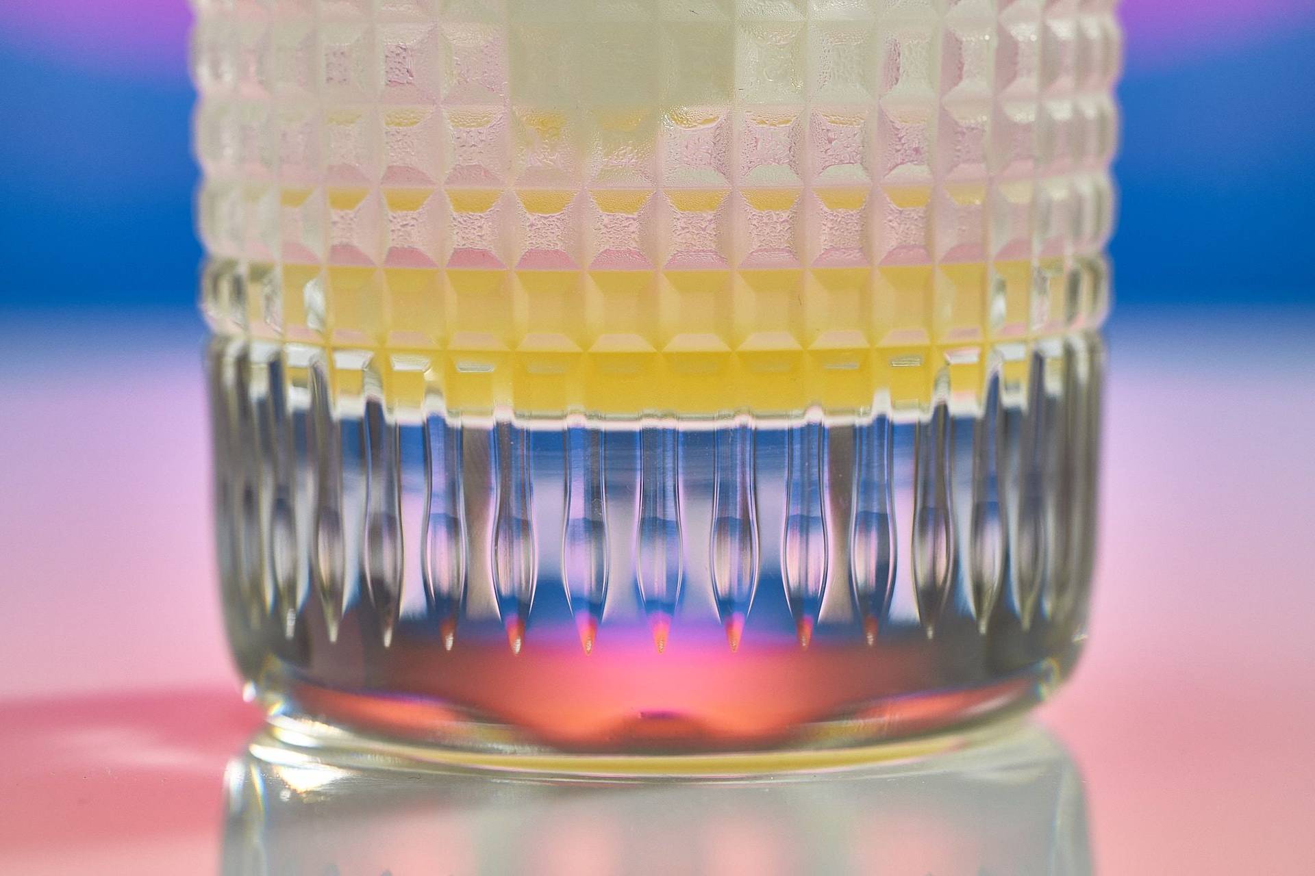 a glass of spicy ginger lemon mocktail on rainbow colored background