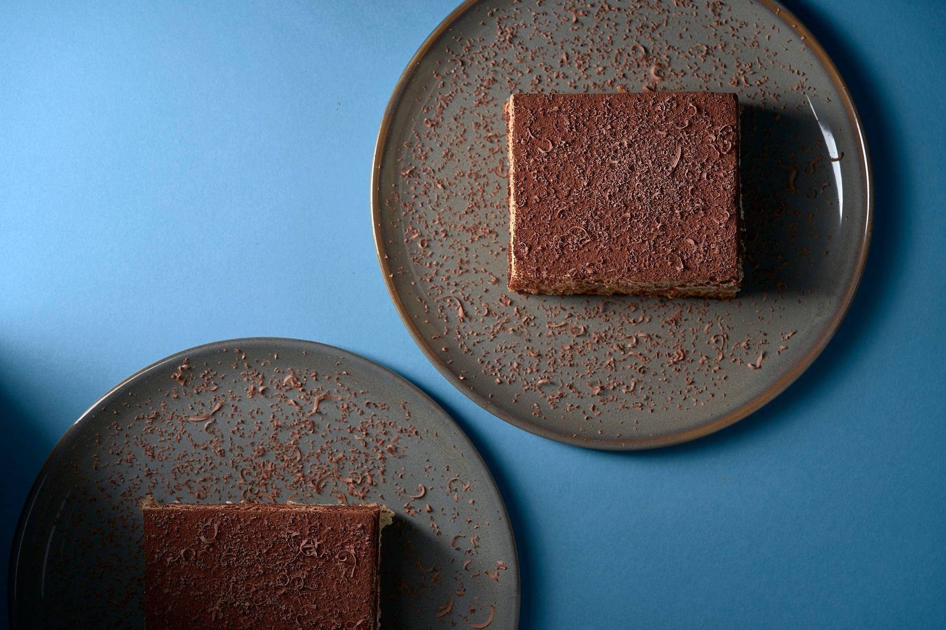 original italienisches tiramisu dessert auf grauem teller mit blauem hintergrund