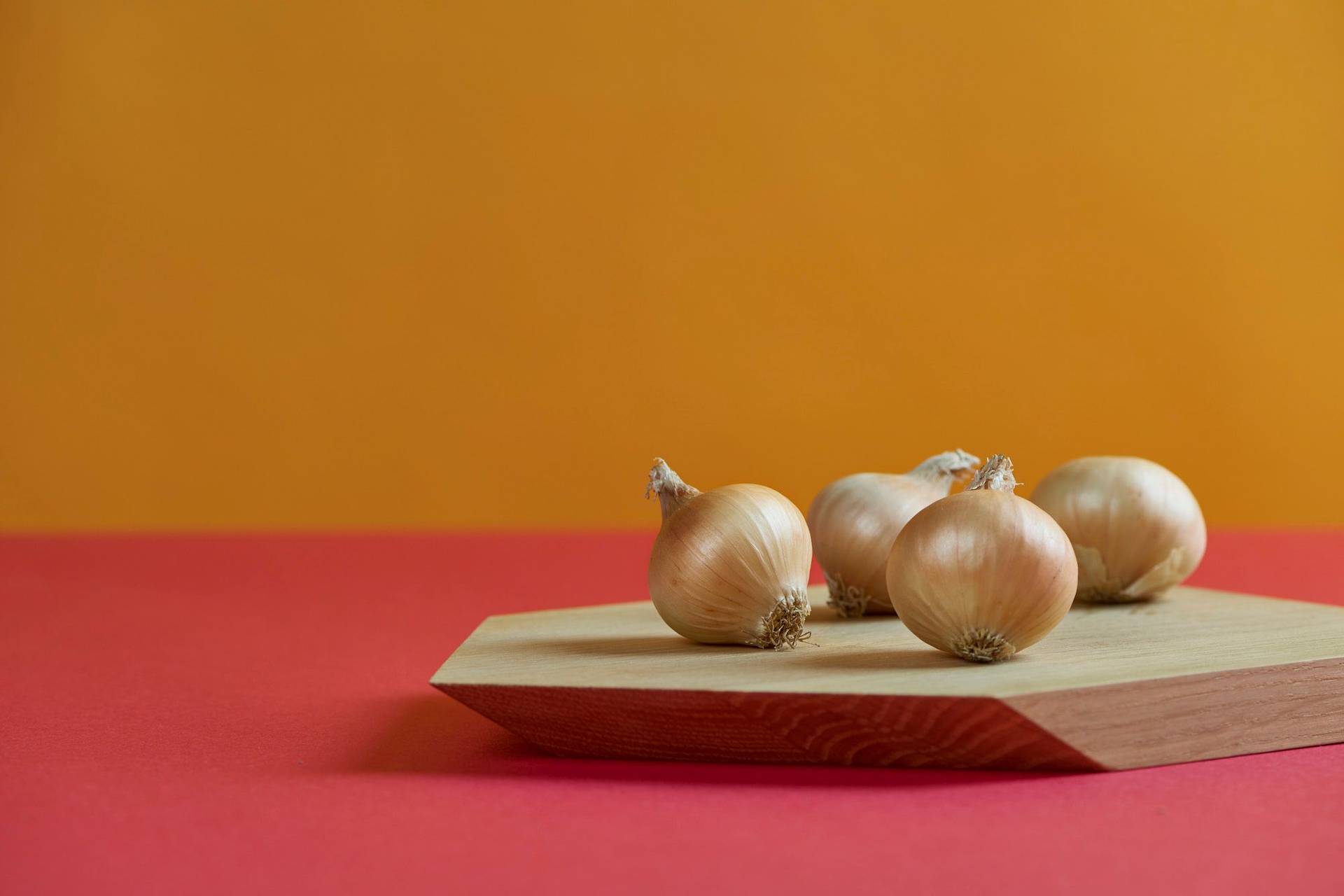 onions on a wooden board with red and yellow background