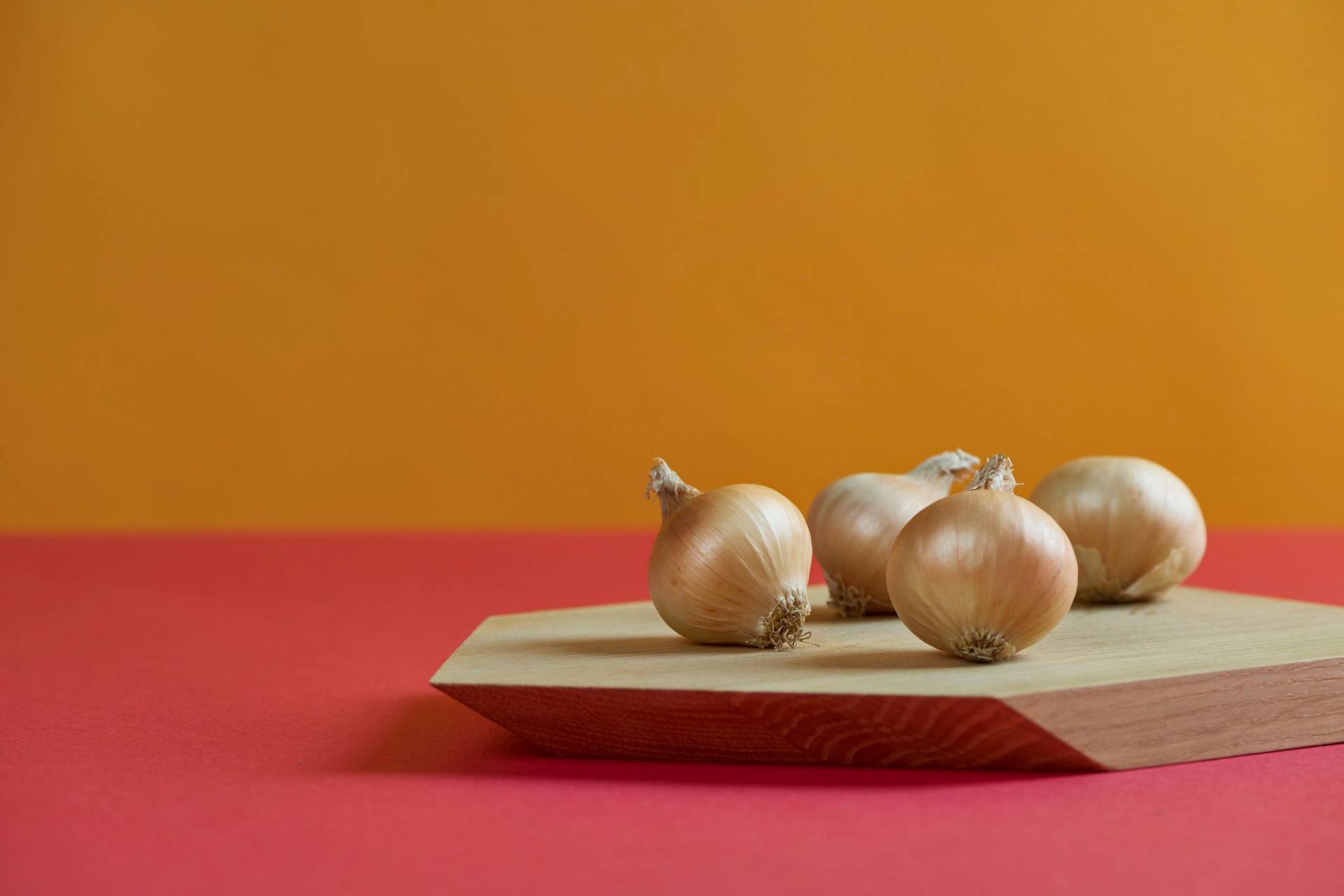 onions onions on a wooden board with red and yellow background