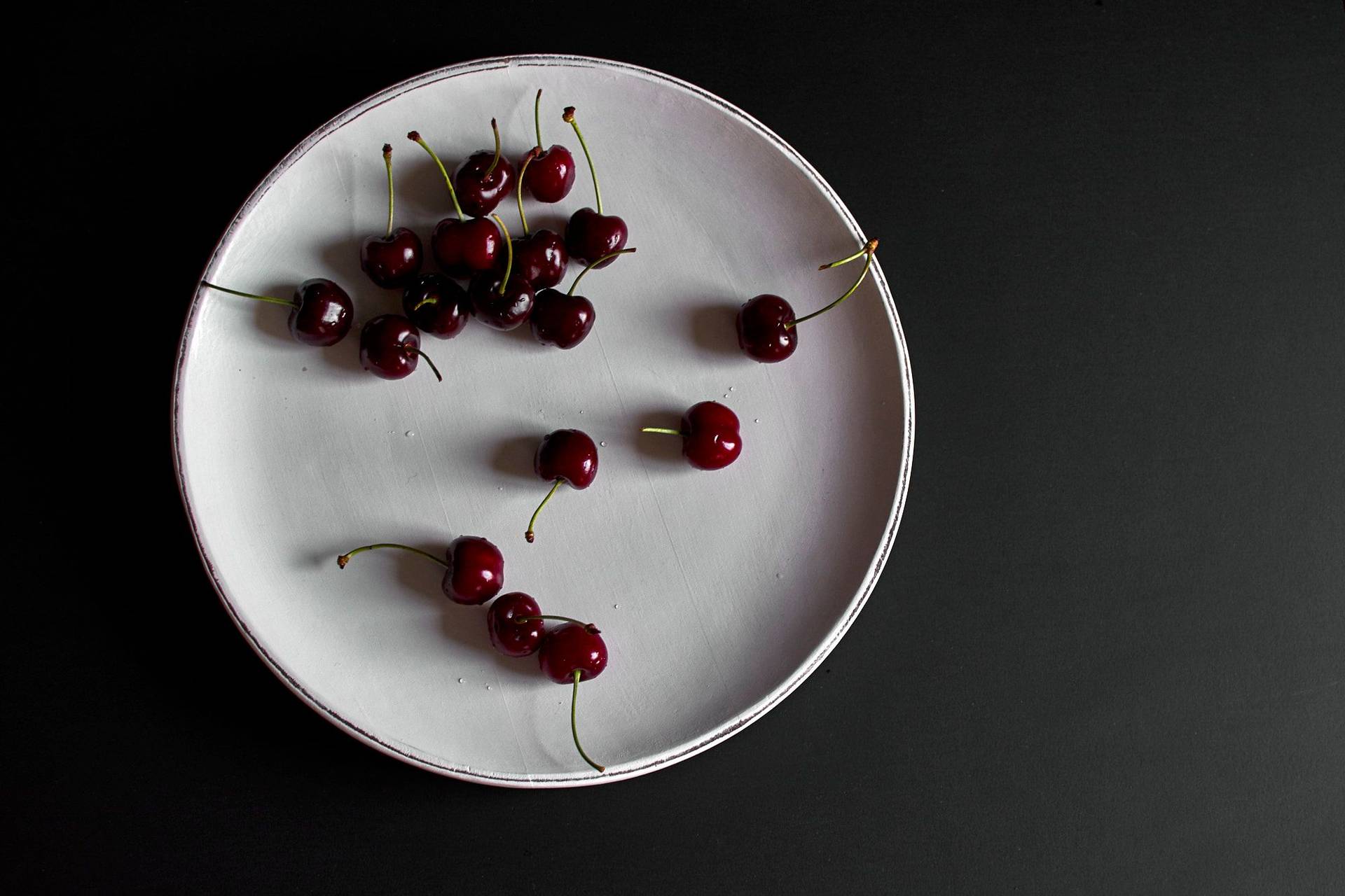 cherries on a white plate with black background