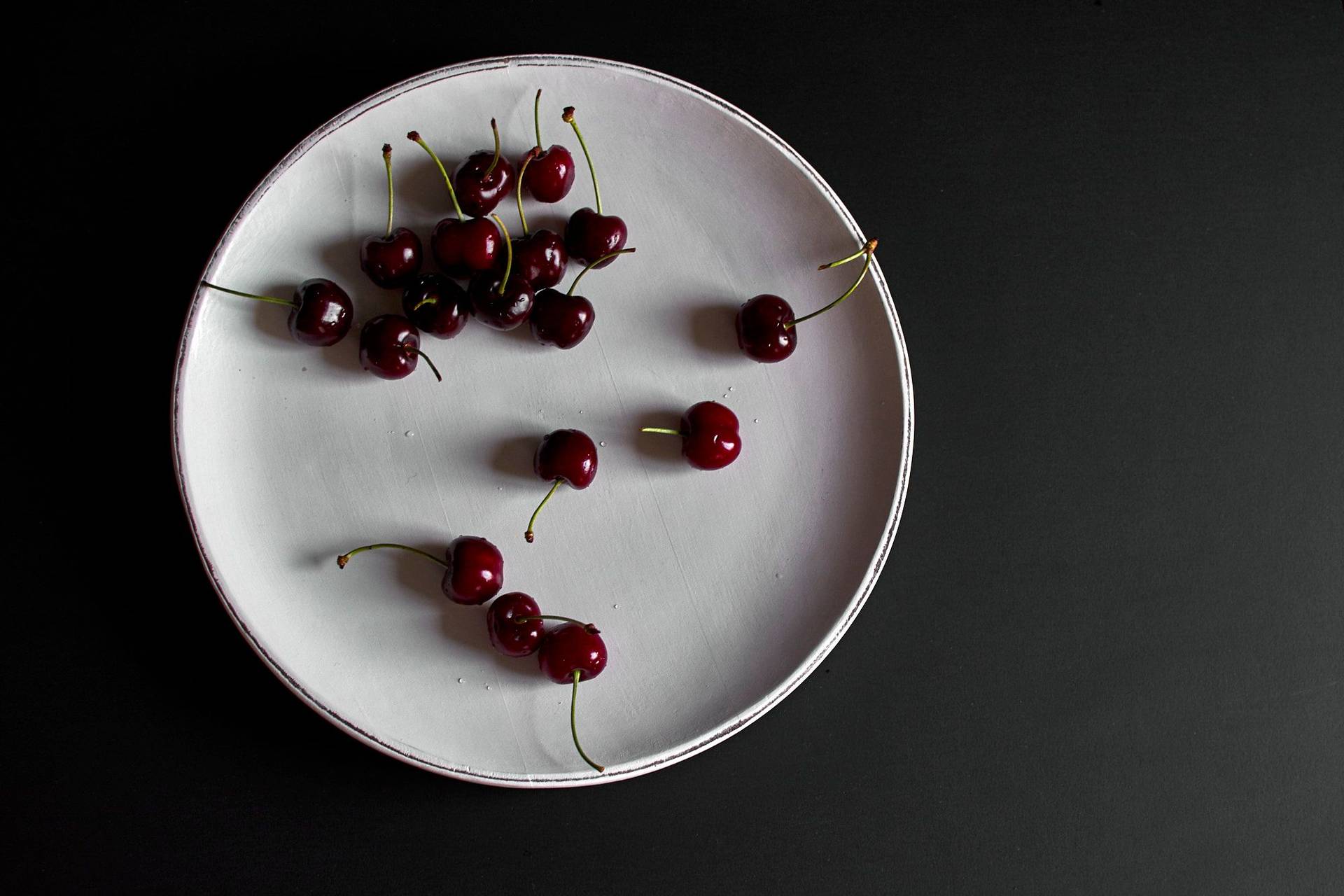 cherries cherries on a white plate with black background