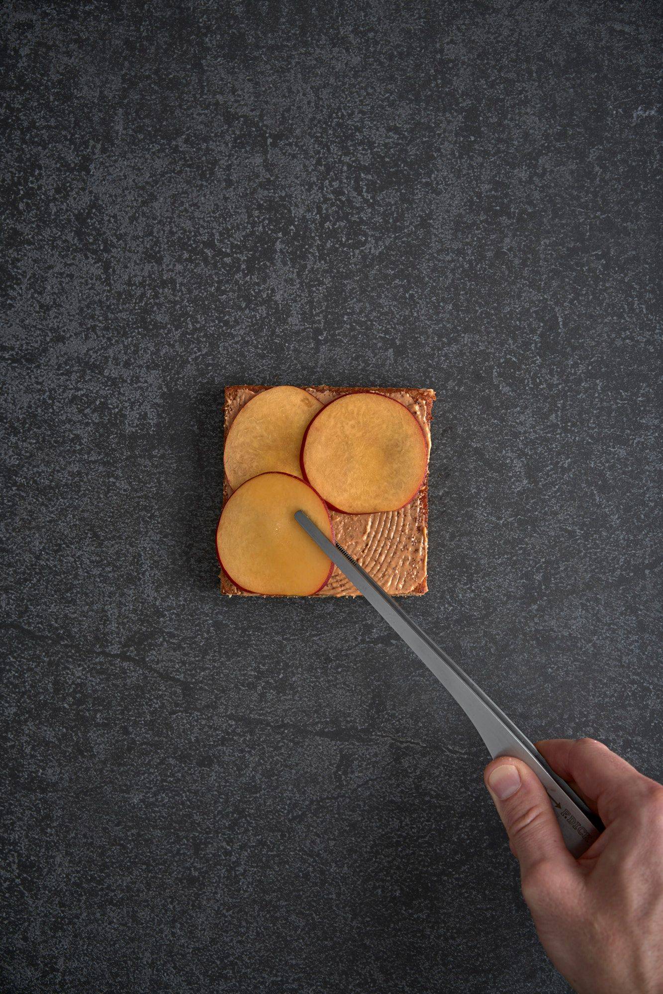 assembling a vegetarian asparagus katsu sando with nectarine and mint mayonnaise on a gray sapienstone top