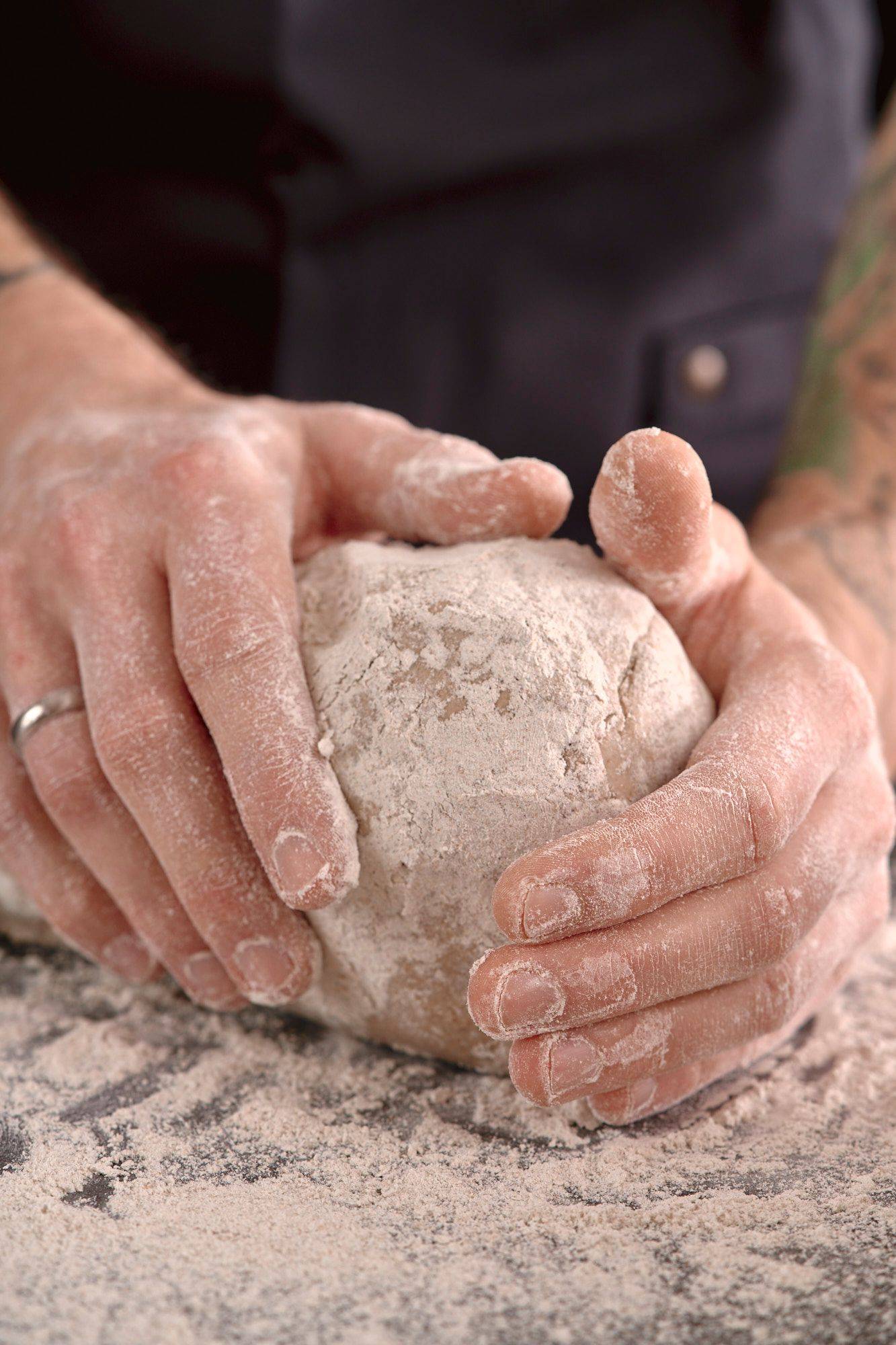 man is kneading rye sourdough in home kitchen