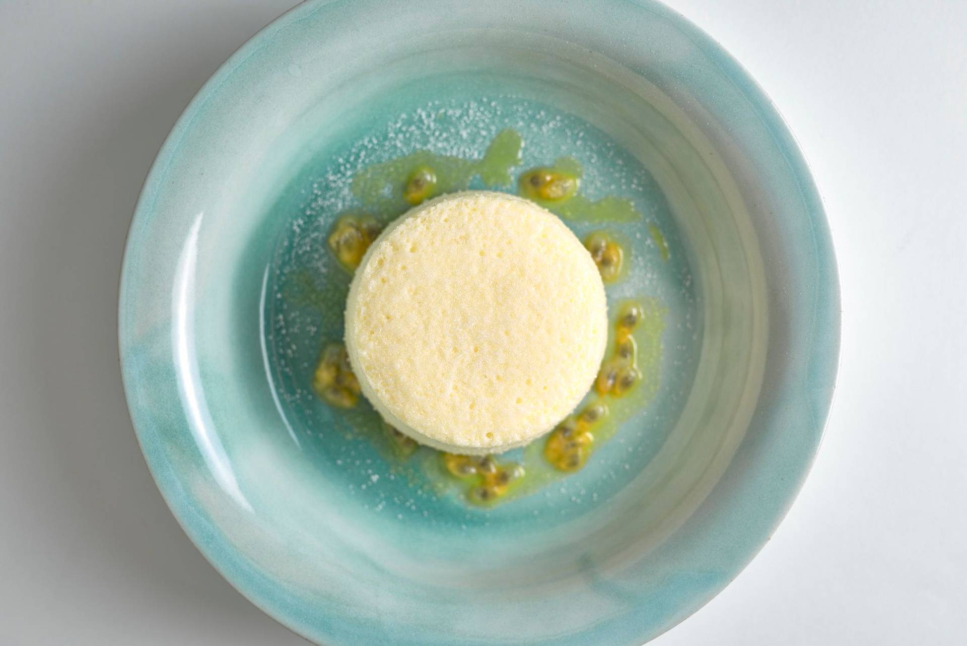 cheesecake souffle with passion fruit and linseed oil in a turquoise plate with white background