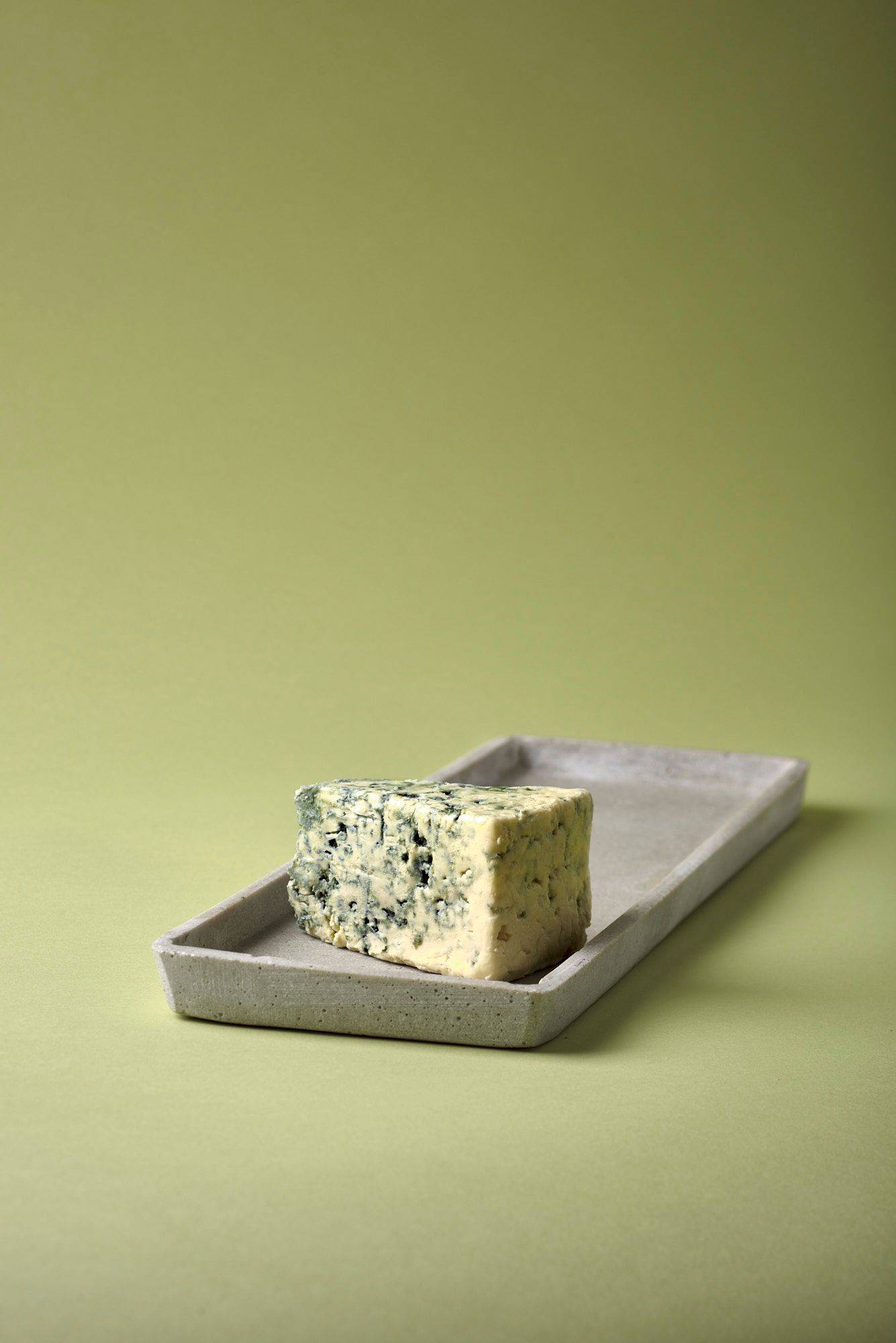 blue cheese on a concrete plate with green background