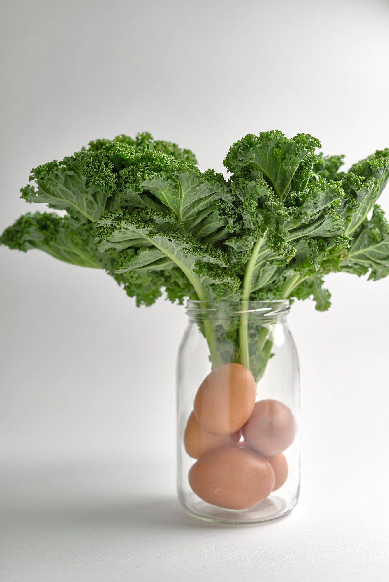 five eggs and kale in a jar with white background