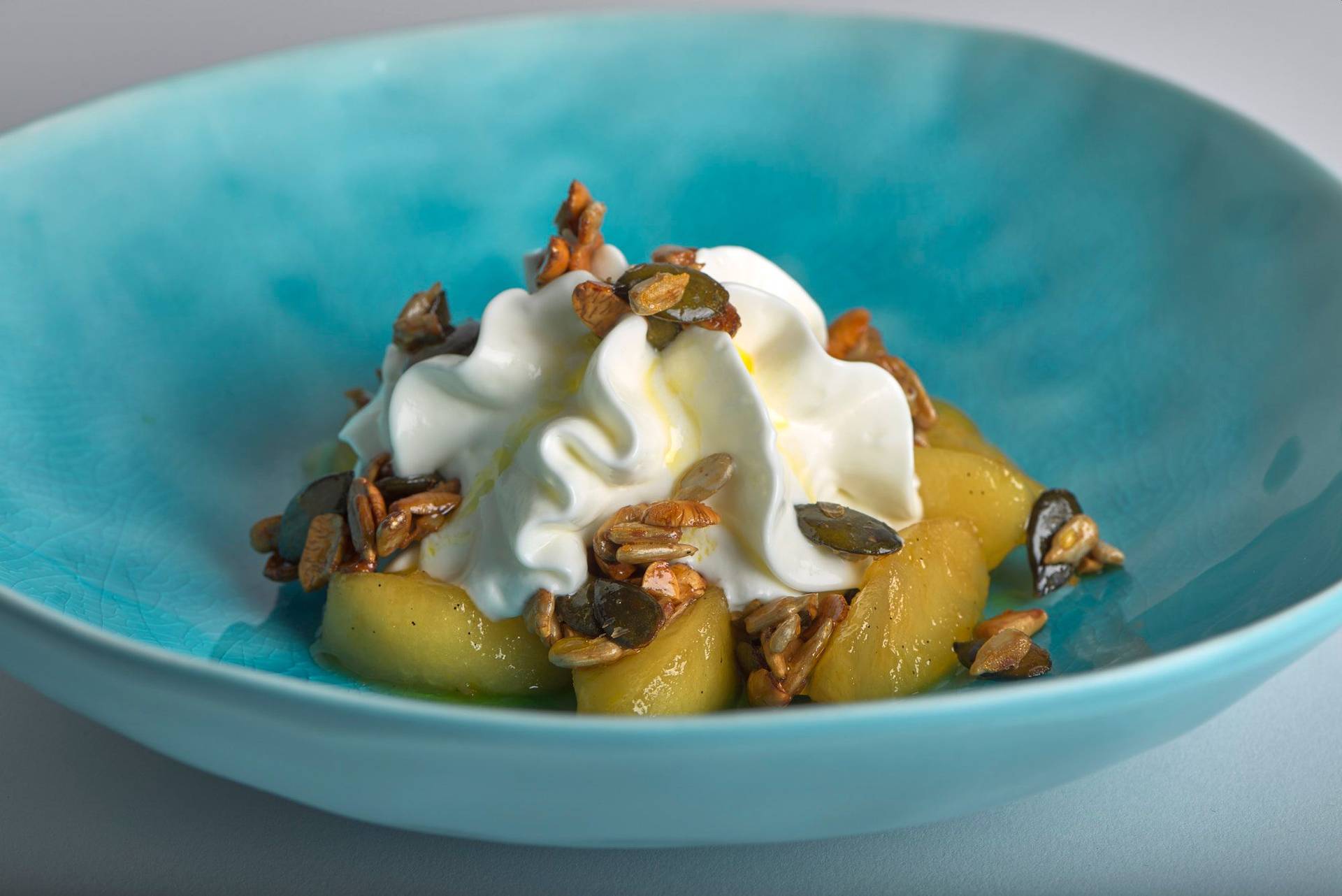 caramelized apples with nuts quark and linseed oil on a turquoise plate with white background