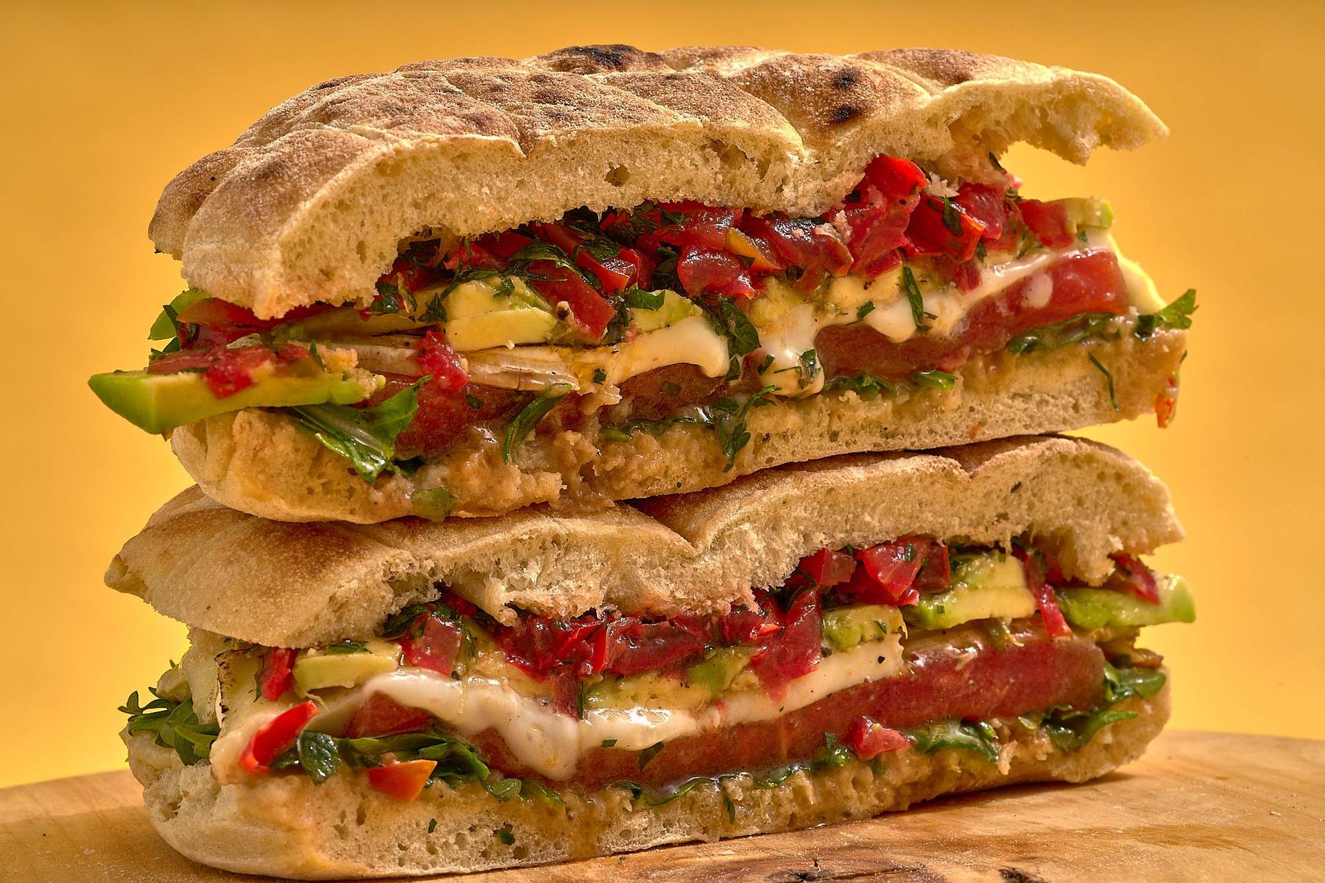 vegetarisches sandwich mit gegrillter wassermelone gremolata knoblauchpaste und käse auf holzbrett mit gelbem hintergrund
