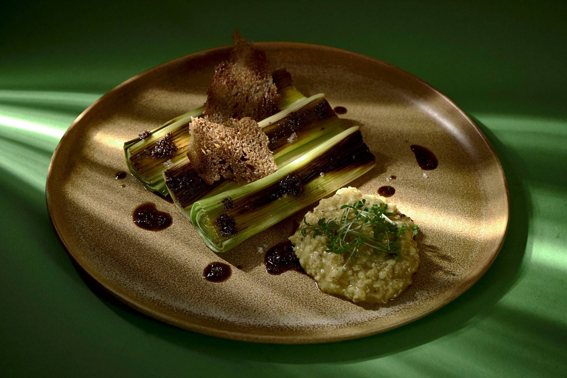 roasted leek with passion fruit porridge and coffee breakfast on a brown ceramic plate with green background