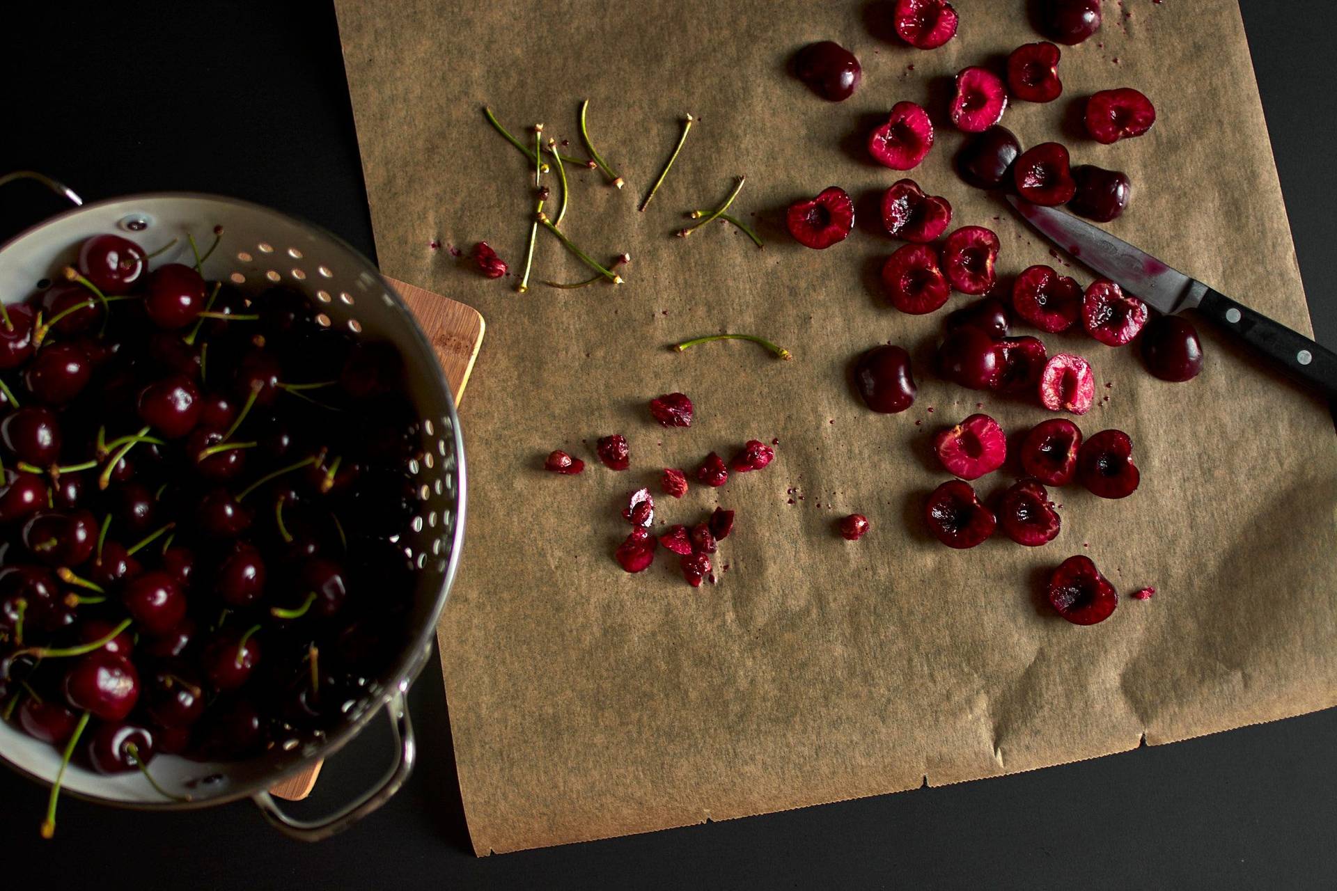 halved cherries on baking paper with black background