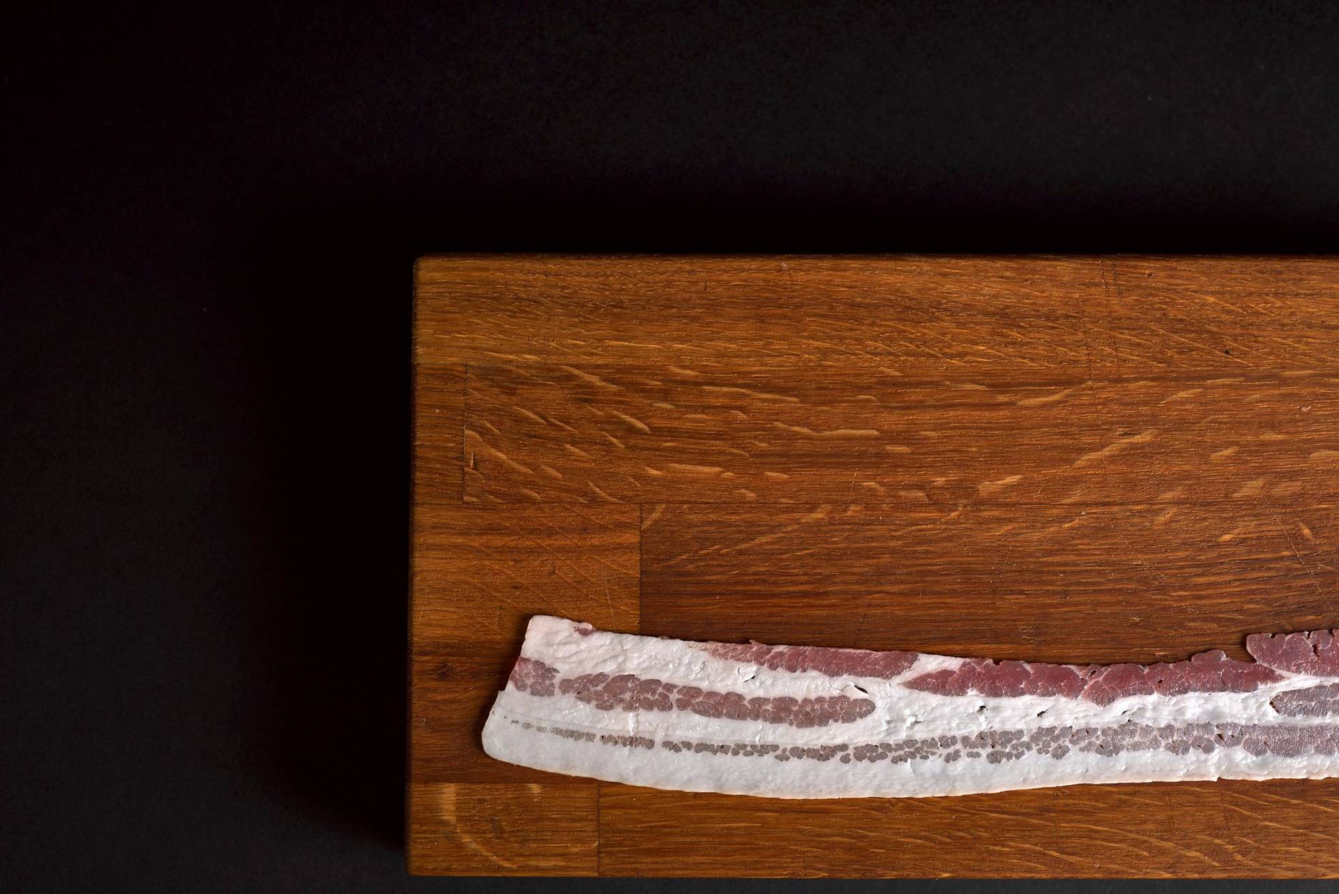 a slice of bacon on a wooden board on a sapienstone top
