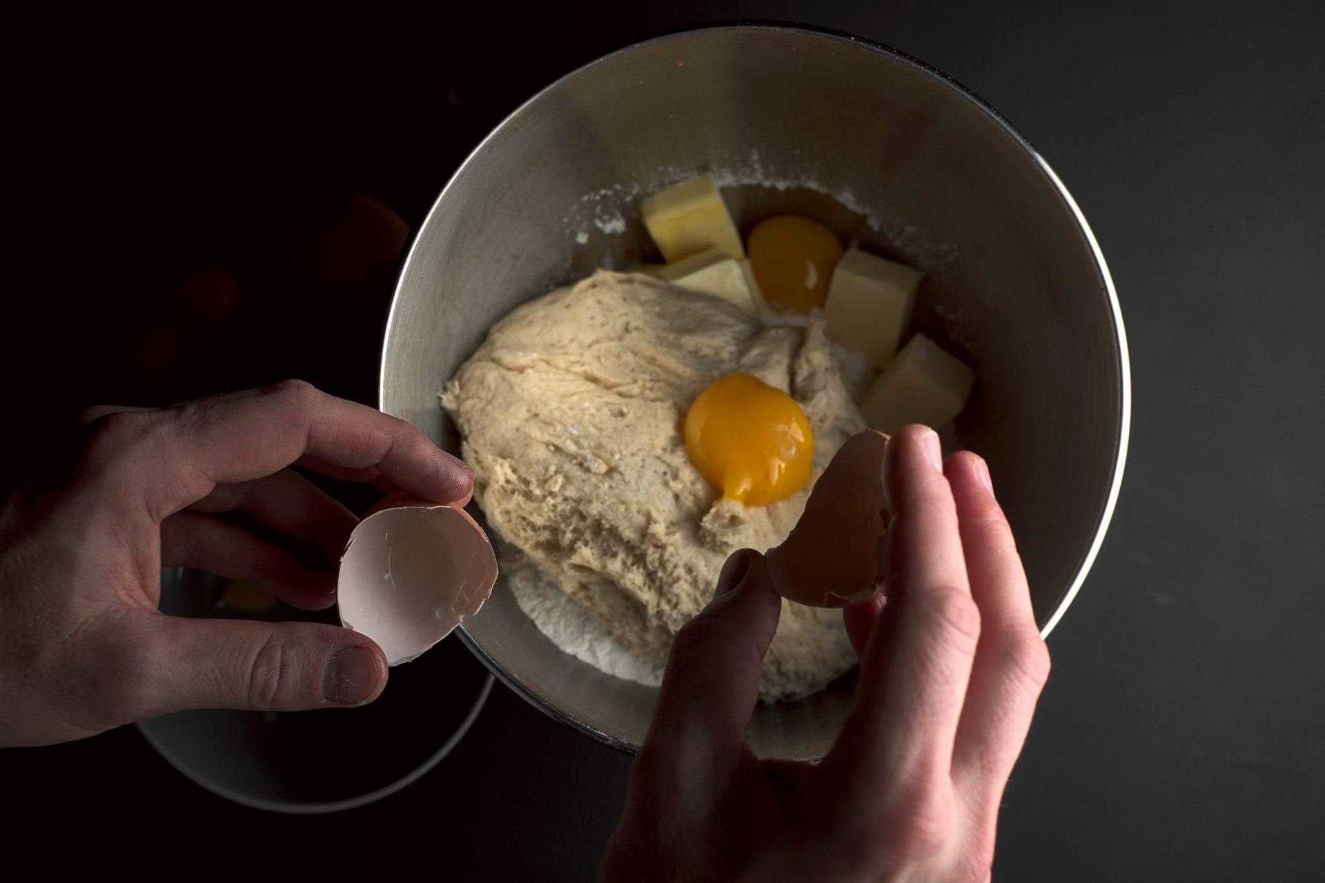 herstellung von brioche teig in einer metal schüssel auf schwarzem hintergrund