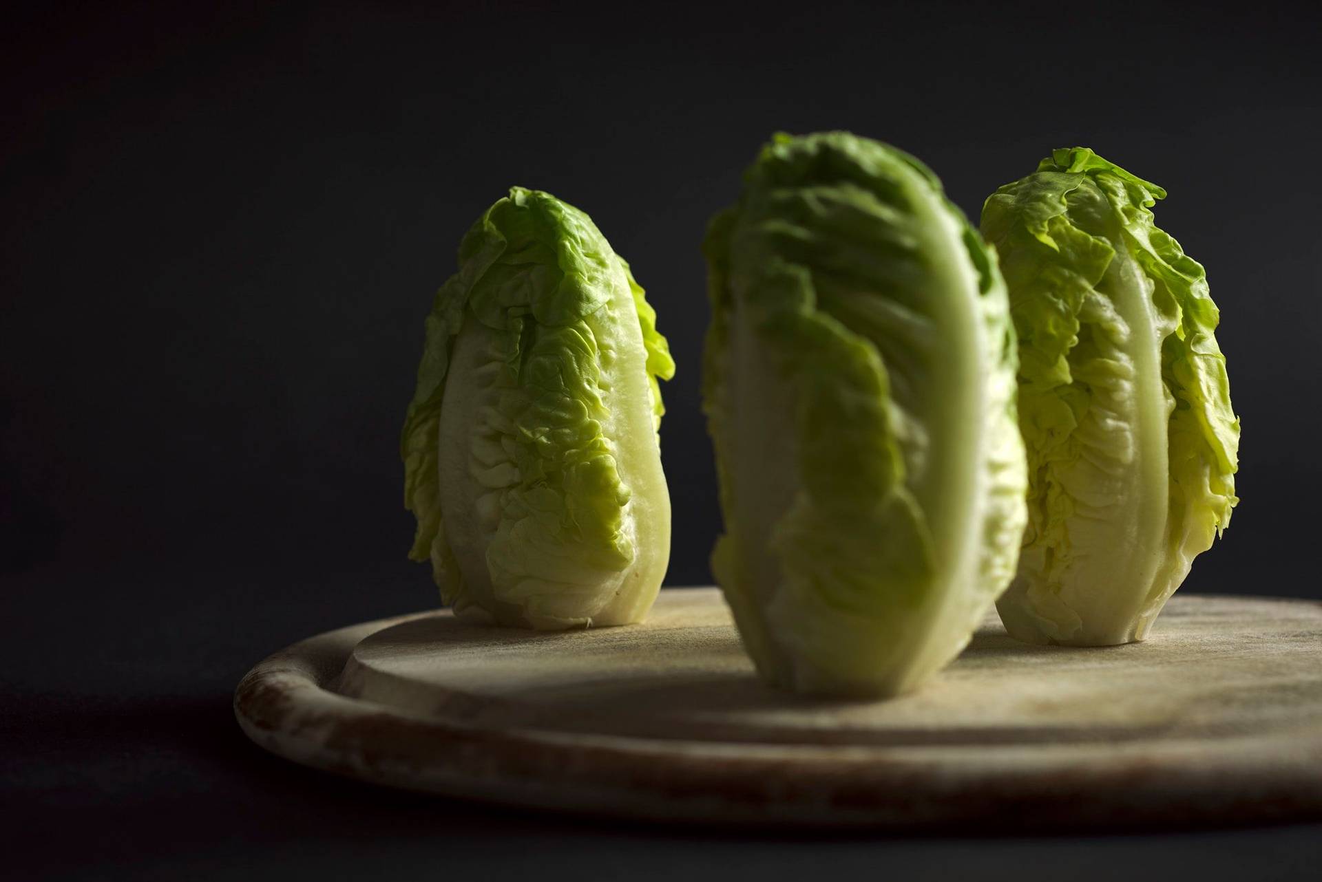 romaine lettuce on a wooden boardcod ceviche with gooseberries in a turquoise ceramic bowl with black background