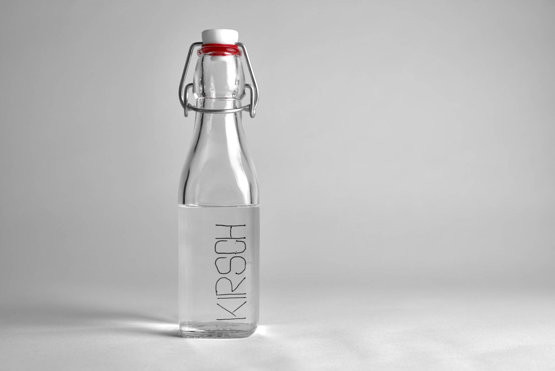 a glass bottle of kirsch liquor on white background