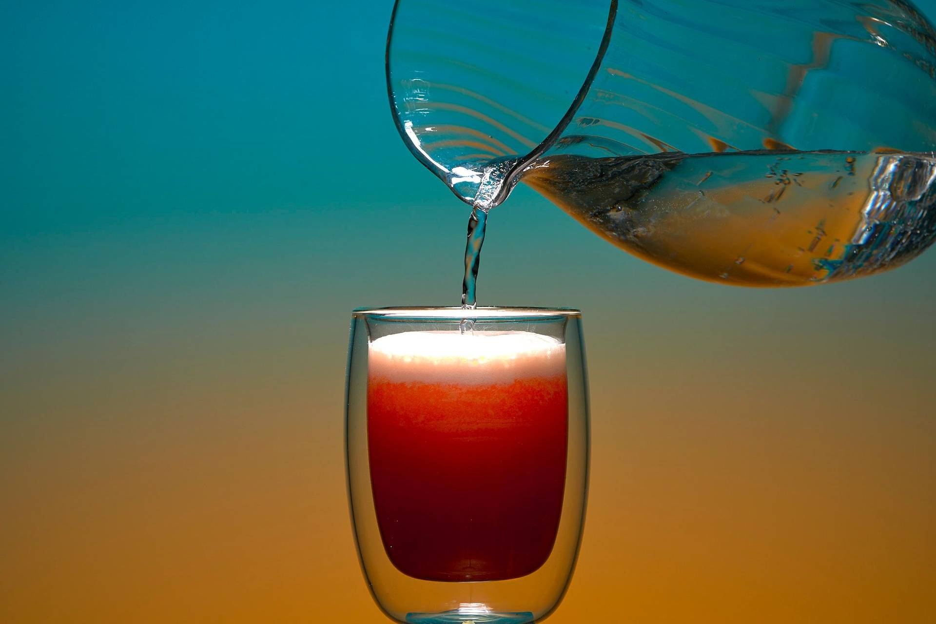 pouring non-alcoholic grapefruit fizz mocktail on blue and orange background