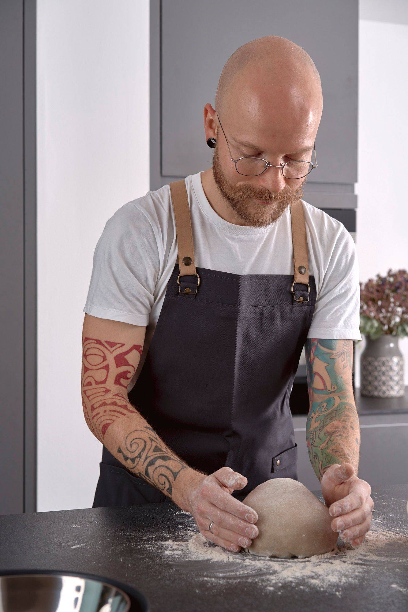 man is kneading rye sourdough in home kitchen