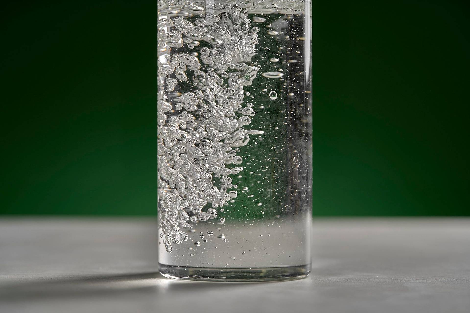 ein glas wasser mit luftblasen auf weißem sapienstone top mit grünem hintergrund