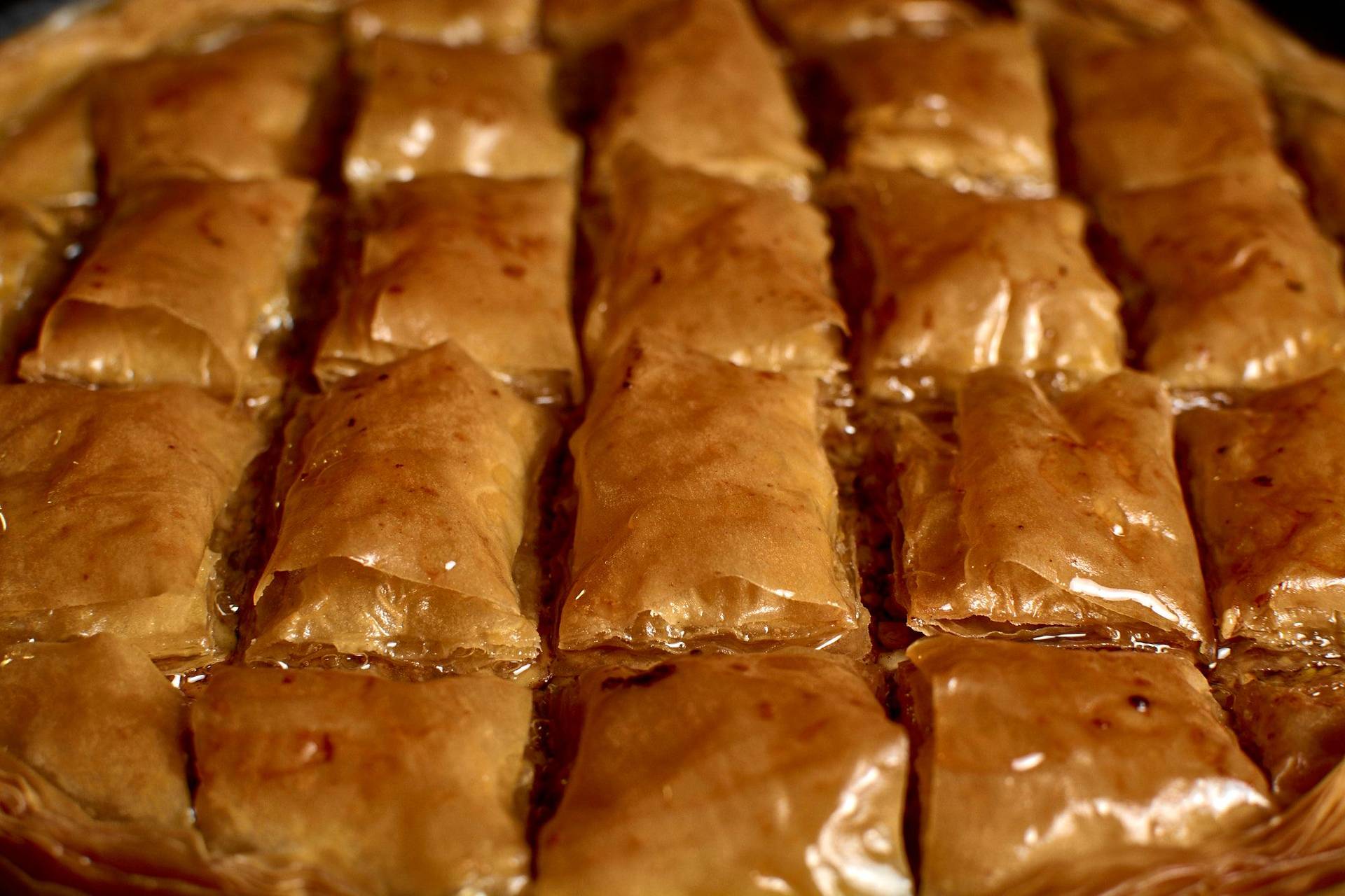 baklava mit haselnüssen und walnüssen in einer backform auf schwarzem hintergrund