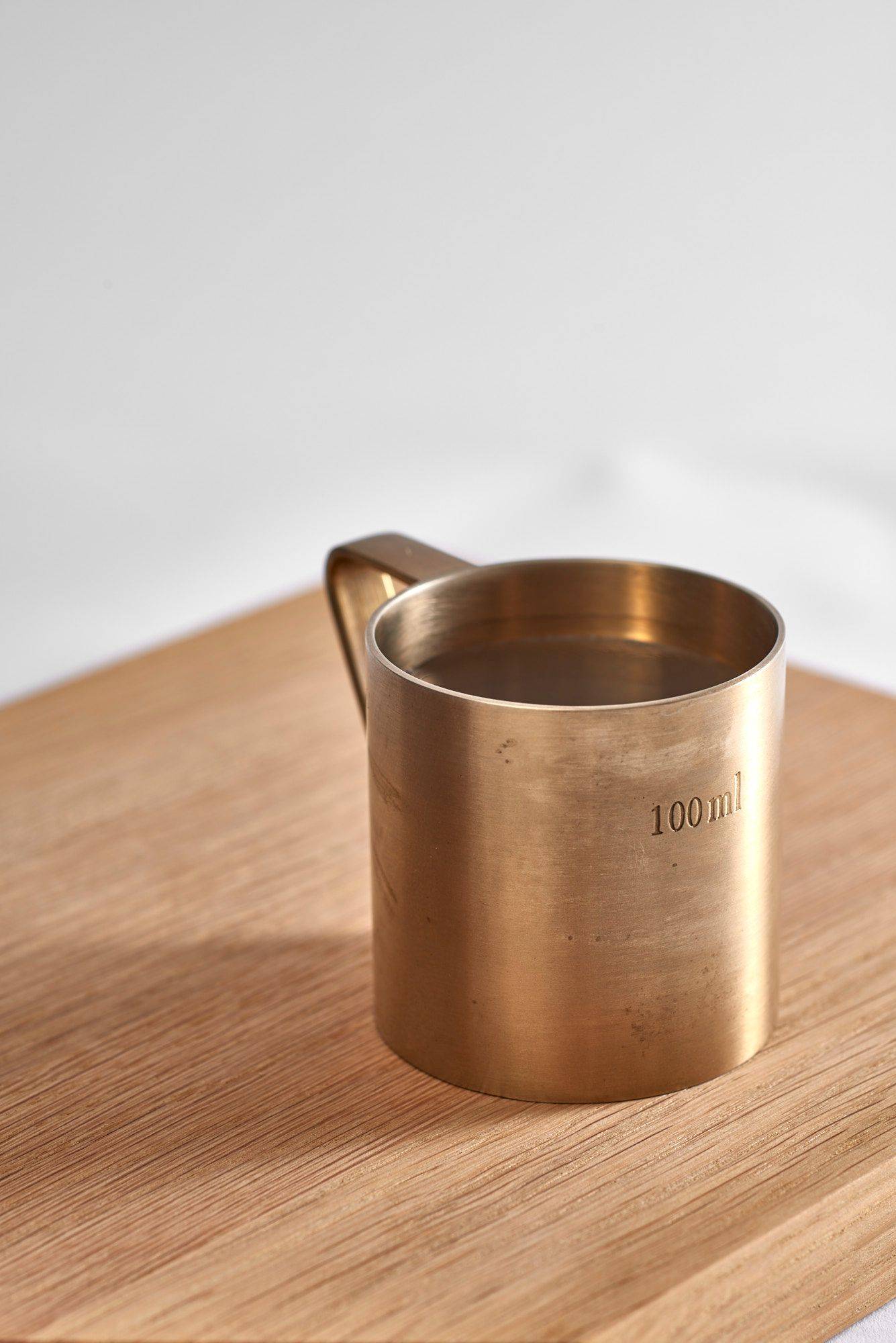 belsazar vermouth in a brass measuring cup on a wooden tray on white background